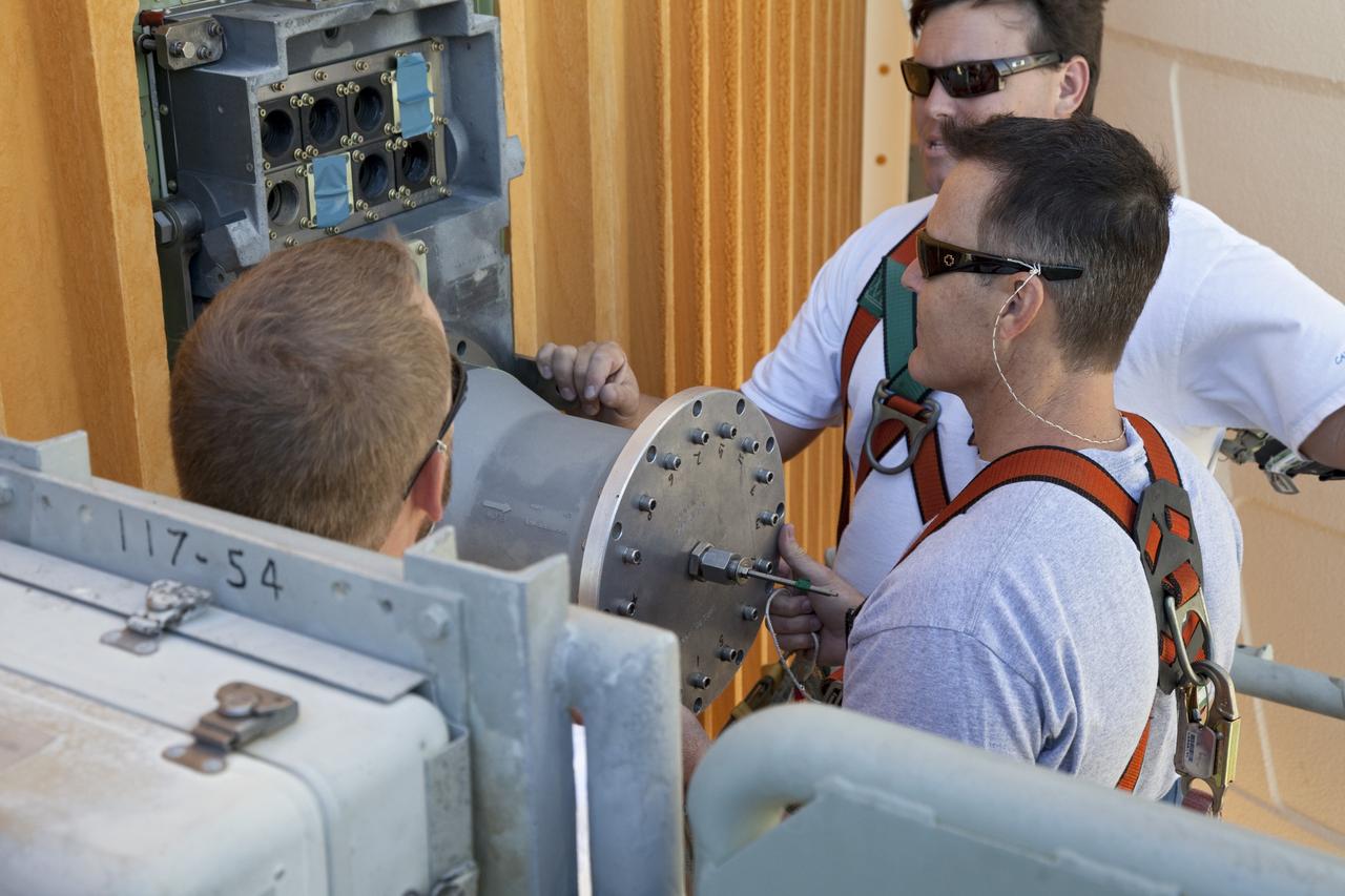 CAPE CANAVERAL, Fla. -- On Launch Pad 39A at NASA's Kennedy Space Center in Florida, workers install a new 7-inch quick disconnect on the ground umbilical carrier plate (GUCP) of space shuttle Discovery's external fuel tank. A hydrogen gas leak at that location during tanking for Discovery's STS-133 mission to the International Space Station caused the launch attempt to be scrubbed Nov. 5. The GUCP is the overboard vent to the pad and the flame stack where the excess hydrogen is burned off.         For more information on STS-133, visit www.nasa.gov/mission_pages/shuttle/shuttlemissions/sts133/. Photo credit: NASA/Frankie Martin