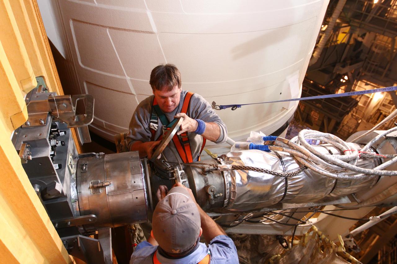 CAPE CANAVERAL, Fla. -- On Launch Pad 39A at NASA's Kennedy Space Center in Florida, technicians reattach the vent line to the ground umbilical carrier plate (GUCP) on space shuttle Discovery's external fuel tank. A hydrogen gas leak at that location during tanking for Discovery's STS-133 mission to the International Space Station caused the launch attempt to be scrubbed Nov. 5.     The GUCP is the overboard vent to the pad and the flame stack where the excess hydrogen is burned off. Discovery's next launch attempt is no earlier than Nov. 30 at 4:02 a.m. EST. For more information on STS-133, visit www.nasa.gov/mission_pages/shuttle/shuttlemissions/sts133/. Photo credit: NASA/Ben Smegelsky