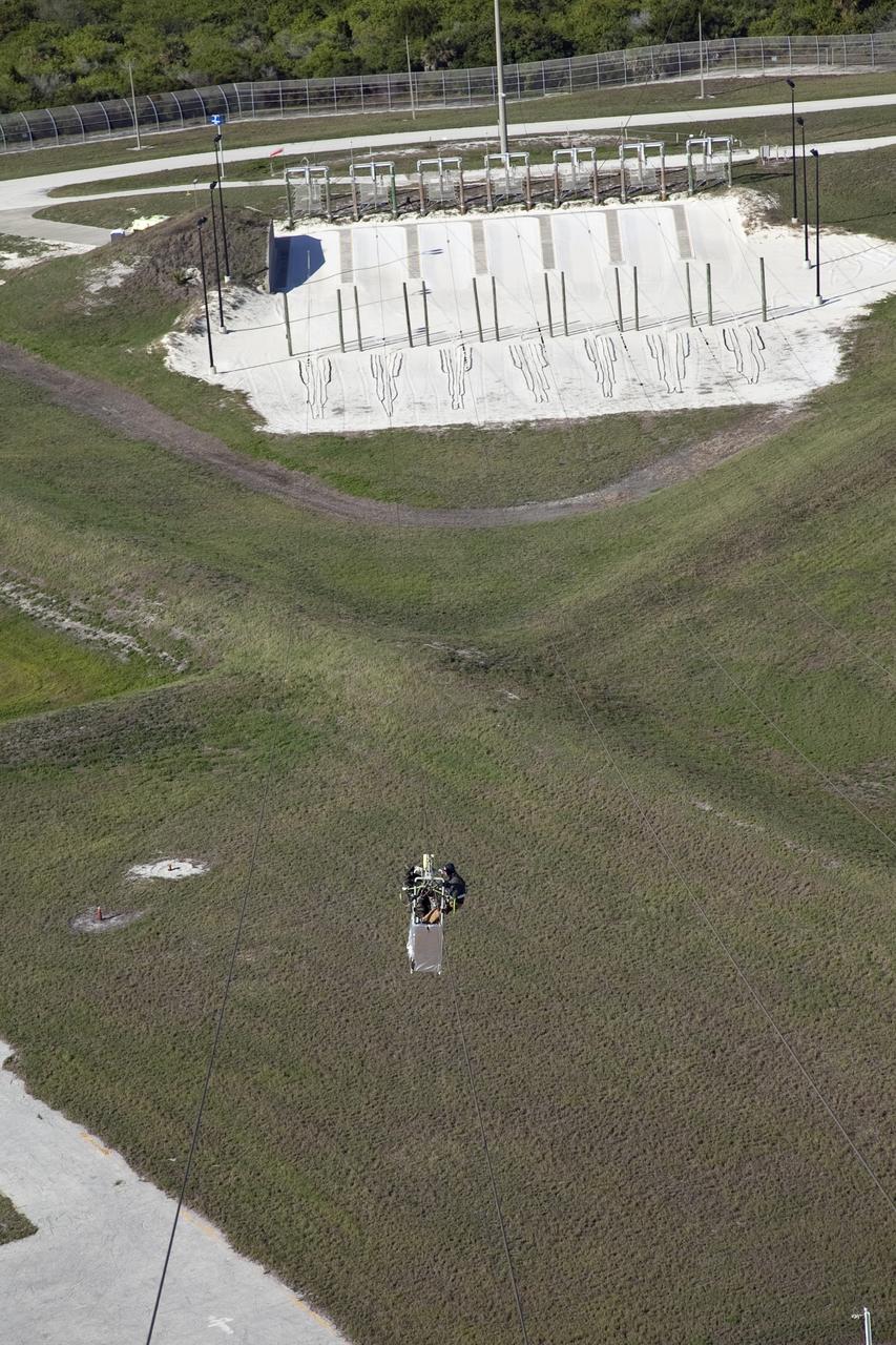 CAPE CANAVERAL, Fla. -- Workers perform routine maintenance on the emergency egress system of Launch Pad 39A at NASA's Kennedy Space Center in Florida. The system includes seven slidewire baskets that can hold up to three people. The slidewire extends from the pad's fixed service structure 195 feet above the ground to a landing zone 1,200 feet to the west.    Photo credit: NASA/Frank Michaux