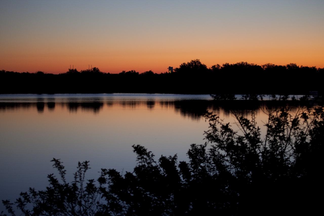 CAPE CANAVERAL, Fla. -- Launch Complex 39 is seen across brackish water as the sun rises at NASA's Kennedy Space Center in Florida. On the left is Launch Pad 39B, which is being restructured for future use. On the right is Launch Pad 39A, where space shuttle Discovery is being prepared for a tanking test. Kennedy coexists with the Merritt Island National Wildlife Refuge, habitat to more than 310 species of birds, 25 mammals, 117 fish and 65 amphibians and reptiles. Photo credit: NASA/Frank Michaux