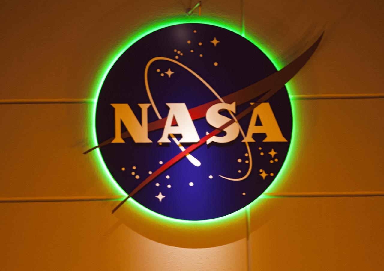 CAPE CANAVERAL, Fla. -- The NASA insignia glistens a shade of green on Kennedy Space Center's Propellants North Administrative and Maintenance Facility in the Launch Complex 39 area. The environmentally friendly facility is slated to be NASA's second Platinum-rated by the U.S. Green Building Council's (USGBC) Leadership in Environmental and Energy Design (LEED) certification system. It will be the space agency's first carbon-neutral facility, which means it will produce enough energy onsite from renewable sources to offset what it requires to operate. The facility consists of a two-story administrative building, which will house managers, mechanics and technicians who fuel spacecraft at Kennedy, and a single-story shop that will be used to store cryogenic fuel transfer equipment.           Photo credit: NASA/Frank Michaux