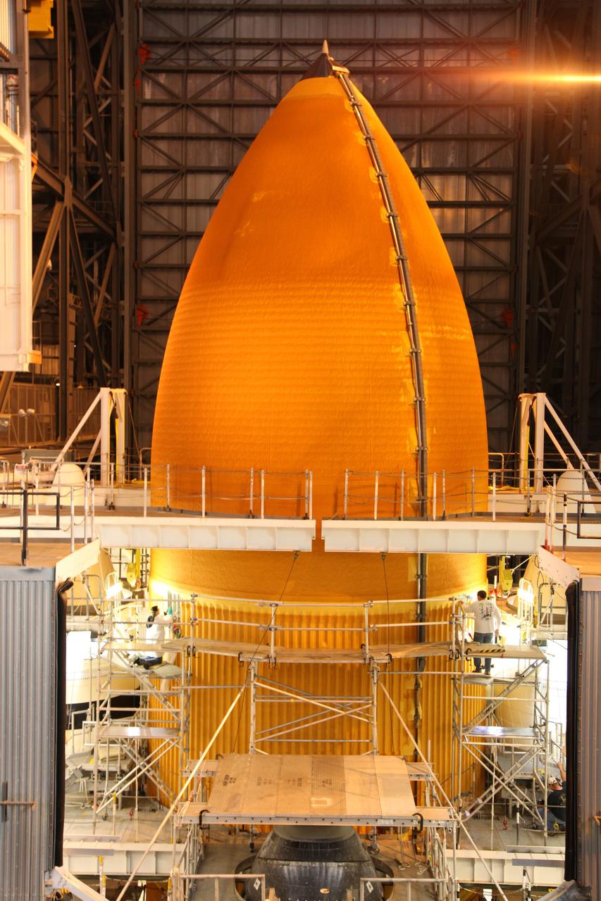 CAPE CANAVERAL, Fla. -- Technicians begin to remove thermal sensors and foam insulation from space shuttle Discovery's external fuel tank in the Vehicle Assembly Building. The sensors will give engineers data about the changes the tank went through with the loading and draining of super-cold propellants during a tanking test on Dec. 17. Below the bright-orange external tank, is the nose of the shuttle, which still is attached to the tank and two solid rocket boosters. Discovery's next launch opportunity to the International Space Station on the STS-133 mission is no earlier than Feb. 3, 2011. For more information on STS-133, visit www.nasa.gov/mission_pages/shuttle/shuttlemissions/sts133/. Photo credit: NASA/Frank Michaux