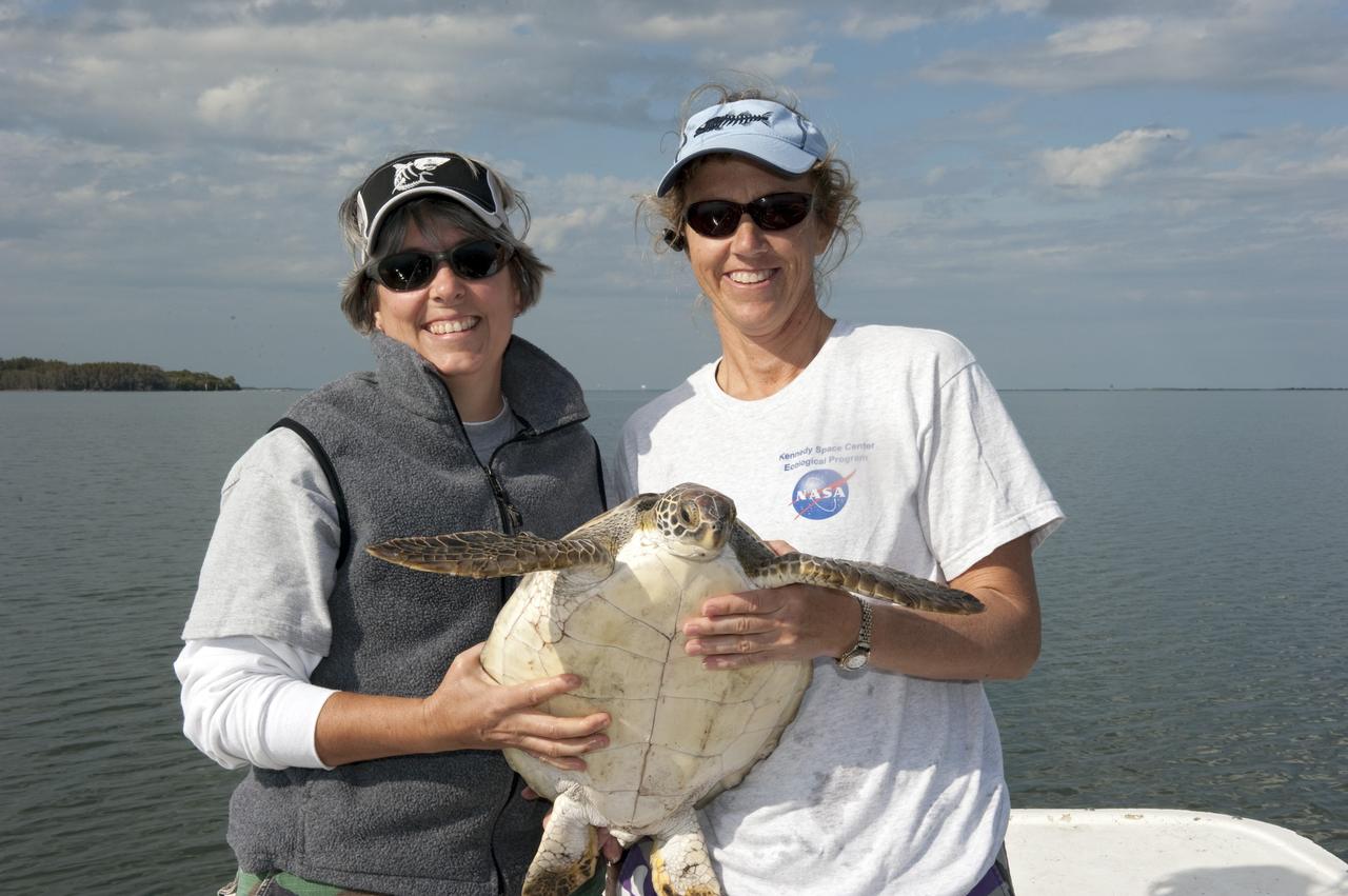 CAPE CANAVERAL, Fla. -- Donna Oddy, left, and Karen Holloway, biologists with Innovative Health Applications at NASA's Kennedy Space Center in Florida, are ready to release an endangered green sea turtle into the Mosquito Lagoon, which is part of Florida's Indian River. The turtle was one of more than 300 that were "stunned" during two cold snaps in December 2010. Turtles that were stunned multiple times will be released in the Sebastian area of the Indian River, which often offers warmer water and could help prevent future stuns as winter progresses.      NASA/Kim Shiflett