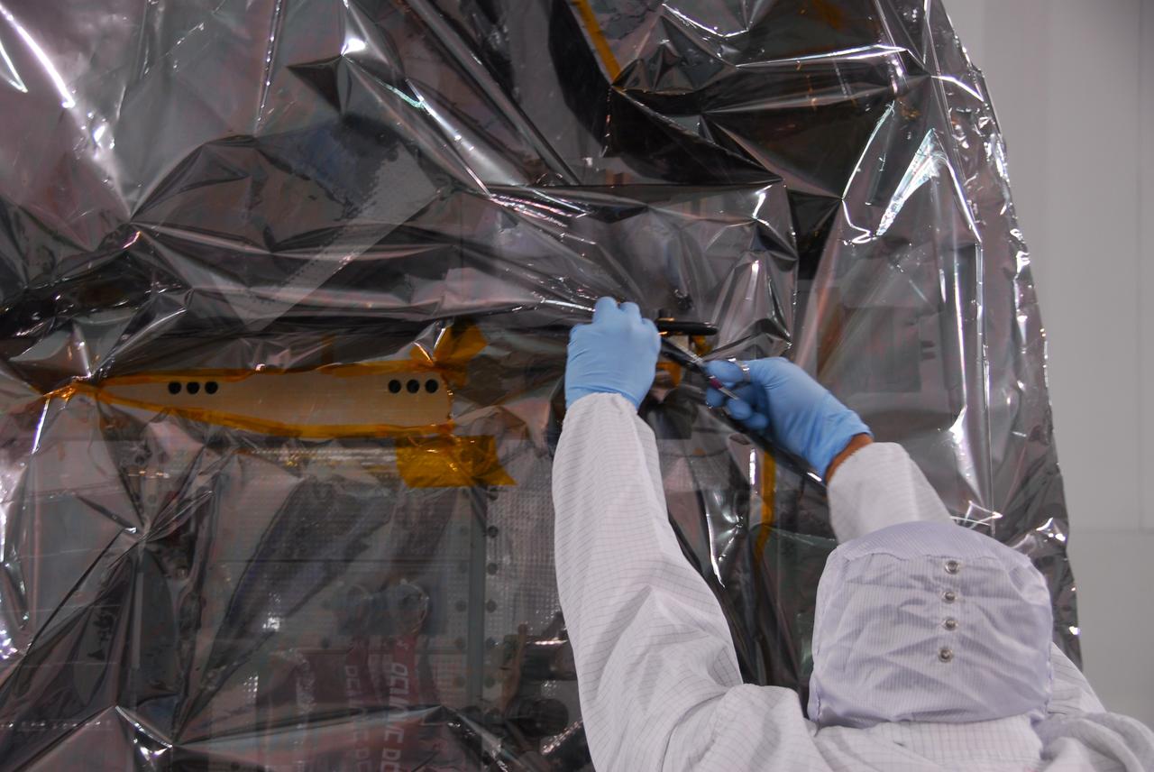 VANDENBERG AIR FORCE BASE, Calif. -- Inside the Astrotech payload processing facility at Vandenberg Air Force Base in California, a technician begins to remove the protective covering surrounding NASA's Glory spacecraft. Next, the spacecraft will be encapsulated in its protective payload fairing before it is transported to Space Launch Complex 576-E and joined with the Taurus XL rocket's third stage. Once Glory reaches orbit, it will collect data on the properties of aerosols and black carbon. It also will help scientists understand how the sun's irradiance affects Earth's climate. Launch is scheduled for 5:09 a.m. EST Feb. 23. For information, visit www.nasa.gov/glory. Photo credit: NASA/Ed Henry, VAFB