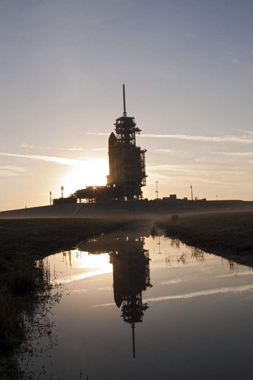 CAPE CANAVERAL, Fla. -- At NASA's Kennedy Space Center in Florida, the sun's early morning rays and space shuttle Discovery are reflected in a pond at Launch Pad 39A. Discovery was moved from the Vehicle Assembly Building with first motion at 7:58 p.m. EST Jan. 31, and was secured or "hard down" on the pad a little before 3 a.m. Feb. 1. Discovery's next launch opportunity to the International Space Station on the STS-133 mission is targeted for Feb. 24. For more information on STS-133, visit www.nasa.gov/mission_pages/shuttle/shuttlemissions/sts133/. Photo credit: NASA/Jack Pfaller