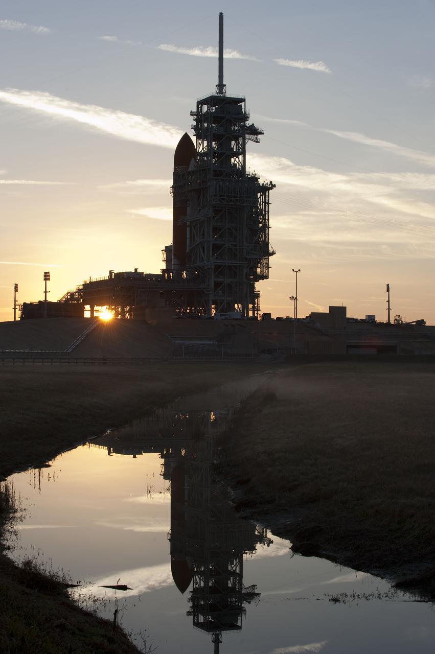 CAPE CANAVERAL, Fla. -- At NASA's Kennedy Space Center in Florida, the sun's early morning rays and space shuttle Discovery are reflected in a pond at Launch Pad 39A. Discovery was moved from the Vehicle Assembly Building with first motion at 7:58 p.m. EST Jan. 31, and was secured or "hard down" on the pad a little before 3 a.m. Feb. 1. Discovery's next launch opportunity to the International Space Station on the STS-133 mission is targeted for Feb. 24. For more information on STS-133, visit www.nasa.gov/mission_pages/shuttle/shuttlemissions/sts133/. Photo credit: NASA/Kim Shiflett