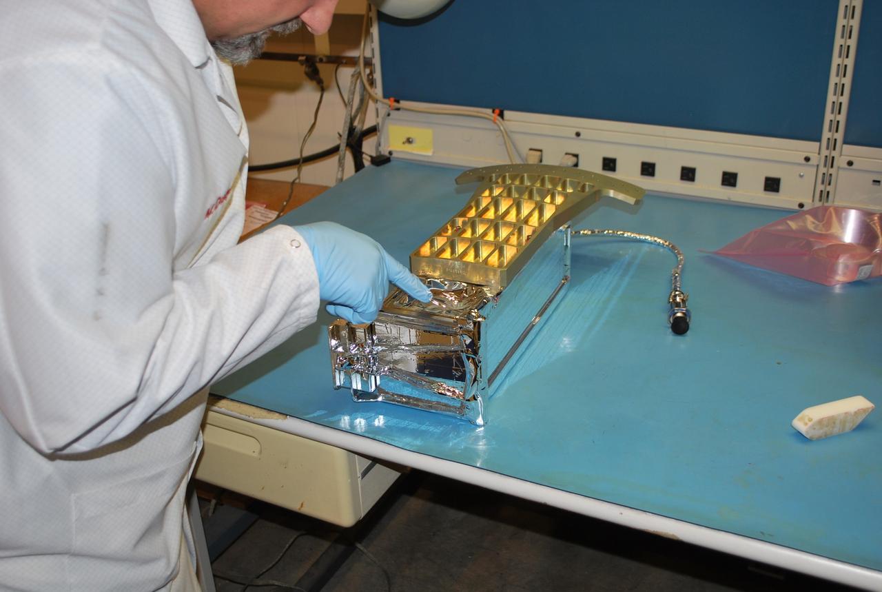 VANDENBERG AIR FORCE BASE, Calif. -- At Vandenberg Air Force Base in California, a technician is pointing to a vent hole in the Poly Picosatellite Orbital Deployer , or P-POD, assembly  after a sheet of silver reflective tape to protect it from the sun had been applied and the bracket interface installed. The bracket will serve as a connection interface between the P-POD and the aft end of the Taurus rocket's third stage. The P-POD will hold three CubeSats or tiny satellites, designed and created by university and college students that will be carried on the Taurus rocket along with the Glory spacecraft.      The Orbital Sciences Corp. Taurus XL rocket will carry NASA's Glory spacecraft into low Earth orbit. Once Glory reaches orbit, it will collect data on the properties of aerosols and black carbon. It also will help scientists understand how the sun's irradiance affects Earth's climate. Launch is scheduled for 5:09 a.m. EST Feb. 23. For information, visit www.nasa.gov/glory. Photo credit: NASA/Randy Beaudoin, VAFB
