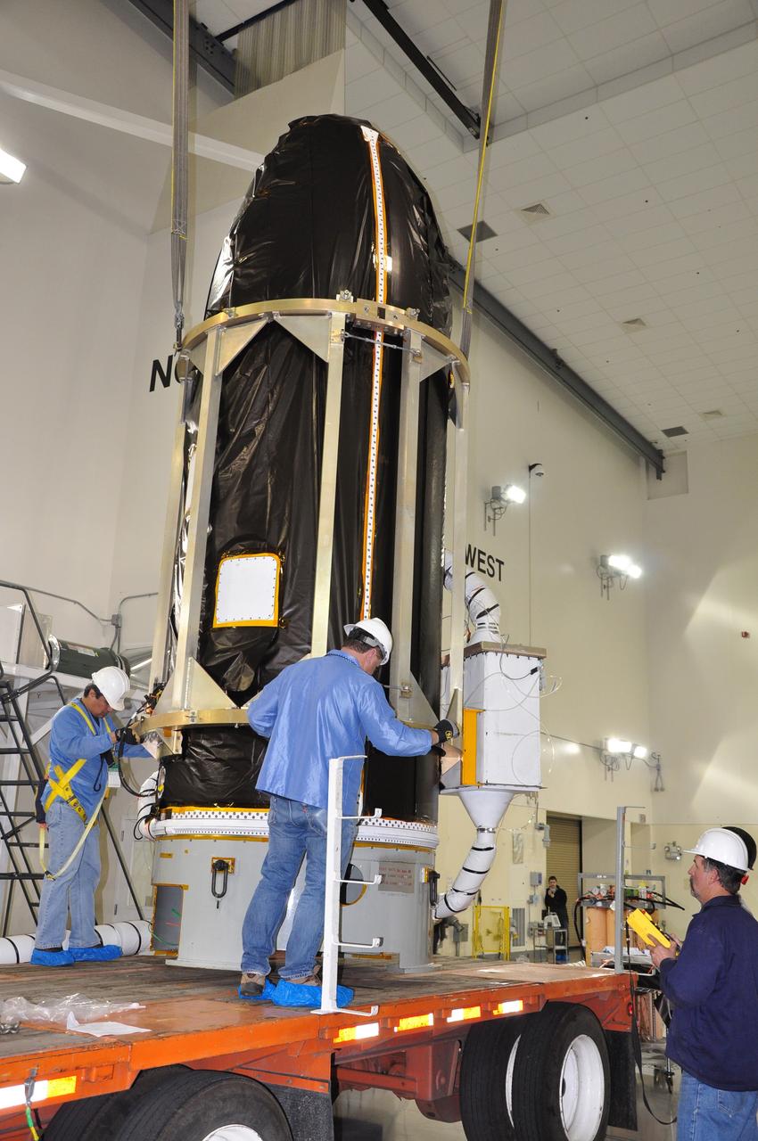 VANDENBERG AIR FORCE BASE, Calif. -- At Astrotech's payload processing facility at Vandenberg Air Force Base in California, workers guide NASA's Glory spacecraft, now completely enclosed in its payload fairing, as it is lowered onto a transporter in the airlock for its move to Space Launch Complex 576-E. There it will be joined with the Taurus XL rocket's third stage. The hose connected to the fairing is an environmental purge that keeps the spacecraft dry and temperature controlled.      The Orbital Sciences Corp. Taurus XL rocket will carry Glory into low Earth orbit. Once Glory reaches orbit, it will collect data on the properties of aerosols and black carbon. It also will help scientists understand how the sun's irradiance affects Earth's climate. Launch is scheduled for 5:09 a.m. EST Feb. 23. For information, visit www.nasa.gov/glory. Photo credit: NASA/Randy Beaudoin, VAFB