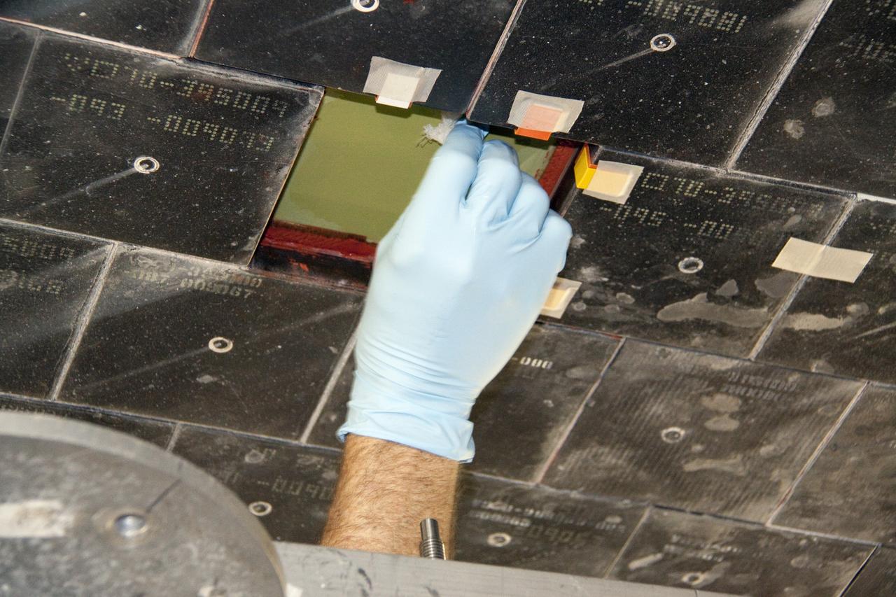 CAPE CANAVERAL, Fla. --  In Orbiter Processing Facility-1 at NASA's Kennedy Space Center in Florida, a thermal protection system technician prepares the surface under space shuttle Atlantis before installing a heat shield tile. The tiles are part of the Orbiter Thermal Protection System, thermal shields to protect against temperatures as high as 3,000 degrees Fahrenheit, which are produced during descent for landing.        Atlantis is being prepared for the STS-135 mission, which will deliver the Raffaello multi-purpose logistics module packed with supplies, logistics and spare parts to the International Space Station. STS-135 is targeted to launch June 28, and will be the last spaceflight for the Space Shuttle Program. Photo credit: NASA/Jack Pfaller