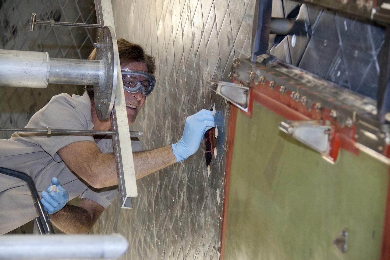CAPE CANAVERAL, Fla. -- In Orbiter Processing Facility-1 at NASA's Kennedy Space Center in Florida, a thermal protection system technician prepares the surface under space shuttle Atlantis before installing a heat shield tile. The tiles are part of the Orbiter Thermal Protection System, thermal shields to protect against temperatures as high as 3,000 degrees Fahrenheit, which are produced during descent for landing.      Atlantis is being prepared for the STS-135 mission, which will deliver the Raffaello multi-purpose logistics module packed with supplies, logistics and spare parts to the International Space Station. STS-135 is targeted to launch June 28, and will be the last spaceflight for the Space Shuttle Program. Photo credit: NASA/Jack Pfaller