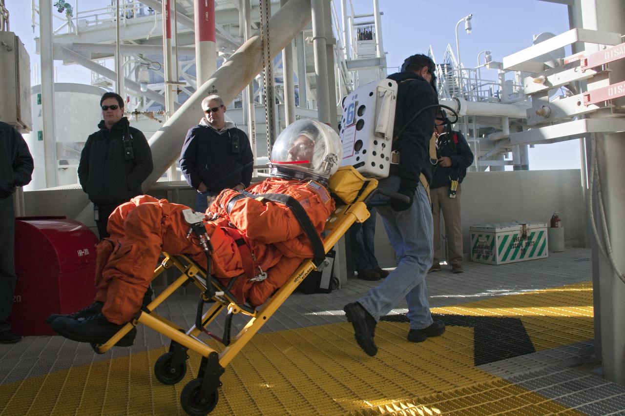 CAPE CANAVERAL, Fla. -- At NASA's Kennedy Space Center in Florida, members of an emergency escape training team perform a simulated evacuation exercise at Launch Pad 39A.           For several days, volunteers portraying astronauts, take part in training exercises which allow teams to practice emergency response procedures, including helicopter evacuation to local hospitals. Training normally involves NASA fire rescue personnel, personnel from the Air Force's 920th Rescue Wing, and medical trauma teams from central Florida hospitals, and is required every 18 months to certify Fire Rescue and Closeout Crew personnel. Photo credit: NASA/Troy Cryder