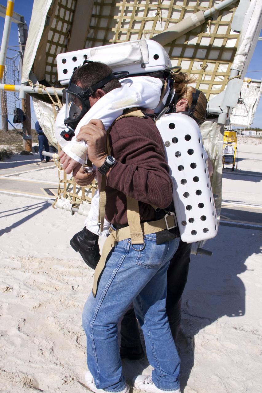 CAPE CANAVERAL, Fla. -- On Launch Pad 39A at NASA's Kennedy Space Center in Florida, members of an emergency escape training team perform a simulated evacuation exercise at the slidewire basket landing site.          For several days, volunteers portraying astronauts, take part in training exercises which allow teams to practice emergency response procedures, including helicopter evacuation to local hospitals. Training normally involves NASA fire rescue personnel, personnel from the Air Force's 920th Rescue Wing, and medical trauma teams from central Florida hospitals, and is required every 18 months to certify Fire Rescue and Closeout Crew personnel. Photo credit: NASA/Troy Cryder