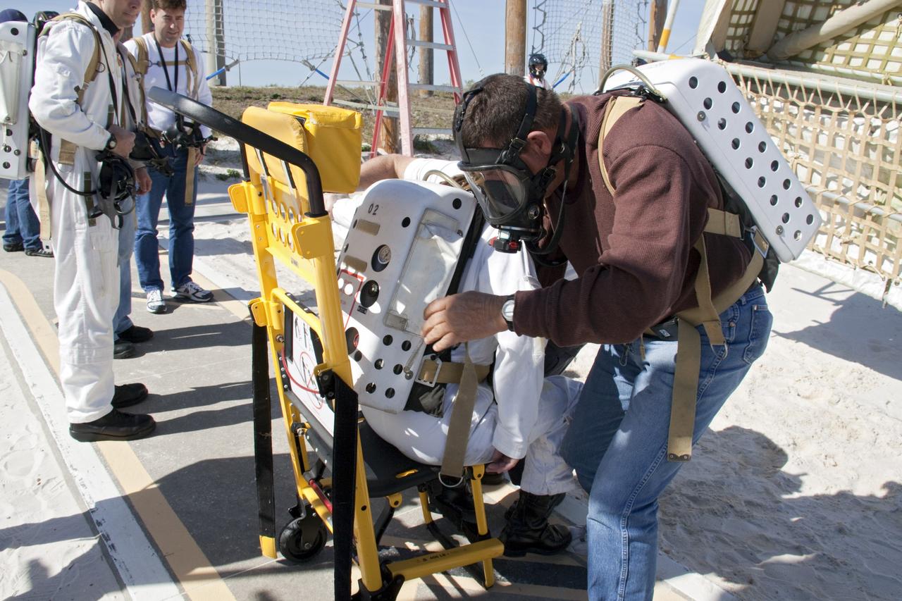CAPE CANAVERAL, Fla. -- On Launch Pad 39A at NASA's Kennedy Space Center in Florida, members of an emergency escape training team perform a simulated evacuation exercise at the slidewire basket landing site.          For several days, volunteers portraying astronauts, take part in training exercises which allow teams to practice emergency response procedures, including helicopter evacuation to local hospitals. Training normally involves NASA fire rescue personnel, personnel from the Air Force's 920th Rescue Wing, and medical trauma teams from central Florida hospitals, and is required every 18 months to certify Fire Rescue and Closeout Crew personnel. Photo credit: NASA/Troy Cryder