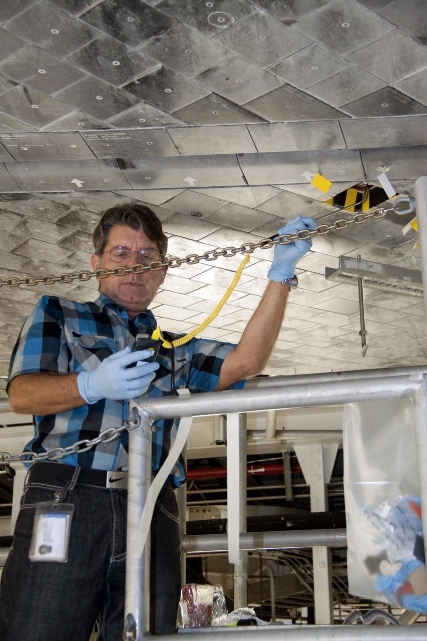 CAPE CANAVERAL, Fla. --  In Orbiter Processing Facility-1 at NASA's Kennedy Space Center in Florida, a thermal protection system technician takes a measurement of the surface in the area on space shuttle Atlantis' underside where a heat shield tile will be installed.           The tiles are part of the Orbiter Thermal Protection System that protects the shuttle against temperatures as high as 3,000 degrees Fahrenheit, which are produced during descent for landing. Atlantis is being prepared for the STS-135 mission, which will carry the Raffaello multi-purpose logistics module packed with supplies, logistics and spare parts to the International Space Station. STS-135 is targeted to launch June 28, and will be the last flight for the Space Shuttle Program. Photo credit: NASA/Jack Pfaller