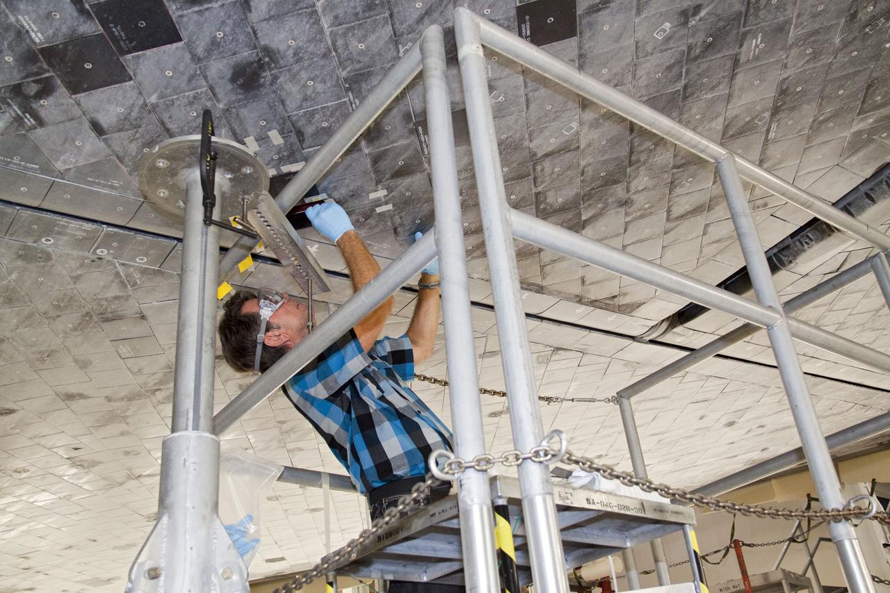 CAPE CANAVERAL, Fla. -- In Orbiter Processing Facility-1 at NASA's Kennedy Space Center in Florida, a thermal protection system technician inspects the area on space shuttle Atlantis' underside before a heat shield tile is installed.      The tiles are part of the Orbiter Thermal Protection System that protects the shuttle against temperatures as high as 3,000 degrees Fahrenheit, which are produced during descent for landing. Atlantis is being prepared for the STS-135 mission, which will carry the Raffaello multi-purpose logistics module packed with supplies, logistics and spare parts to the International Space Station. STS-135 is targeted to launch June 28, and will be the last flight for the Space Shuttle Program. Photo credit: NASA/Jack Pfaller