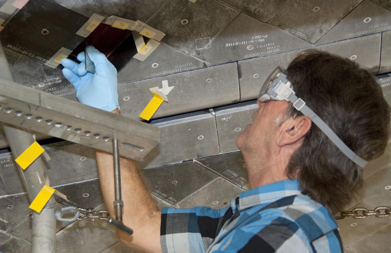 CAPE CANAVERAL, Fla. -- In Orbiter Processing Facility-1 at NASA's Kennedy Space Center in Florida, a thermal protection system technician installs a gap filler in the area on space shuttle Atlantis' underside before a heat shield tile is installed.    The tiles are part of the Orbiter Thermal Protection System that protects the shuttle against temperatures as high as 3,000 degrees Fahrenheit, which are produced during descent for landing. Atlantis is being prepared for the STS-135 mission, which will carry the Raffaello multi-purpose logistics module packed with supplies, logistics and spare parts to the International Space Station. STS-135 is targeted to launch June 28, and will be the last flight for the Space Shuttle Program. Photo credit: NASA/Jack Pfaller