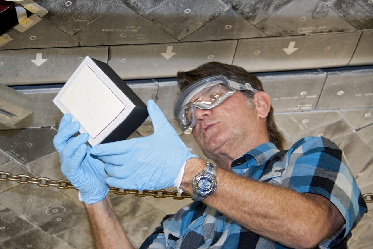 CAPE CANAVERAL, Fla. -- In Orbiter Processing Facility-1 at NASA's Kennedy Space Center in Florida, a thermal protection system technician closely inspects a heat shield tile for space shuttle Atlantis before securing it into position.        The tiles are part of the Orbiter Thermal Protection System that protects the shuttle against temperatures as high as 3,000 degrees Fahrenheit, which are produced during descent for landing. Atlantis is being prepared for the STS-135 mission, which will carry the Raffaello multi-purpose logistics module packed with supplies, logistics and spare parts to the International Space Station. STS-135 is targeted to launch June 28, and will be the last flight for the Space Shuttle Program. Photo credit: NASA/Jack Pfaller