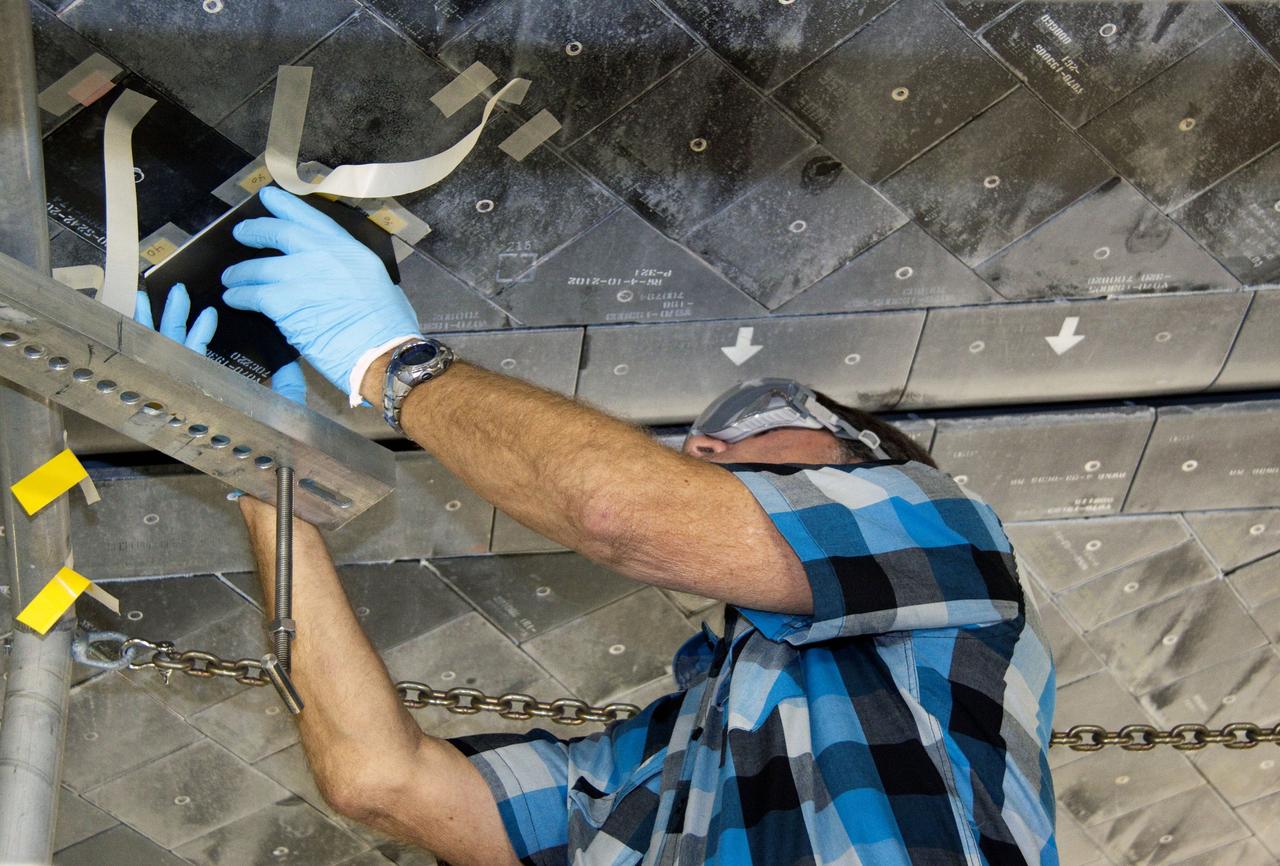 CAPE CANAVERAL, Fla. -- In Orbiter Processing Facility-1 at NASA's Kennedy Space Center in Florida, a thermal protection system technician places a heat shield tile into position under space shuttle Atlantis.      The tiles are part of the Orbiter Thermal Protection System that protects the shuttle against temperatures as high as 3,000 degrees Fahrenheit, which are produced during descent for landing. Atlantis is being prepared for the STS-135 mission, which will carry the Raffaello multi-purpose logistics module packed with supplies, logistics and spare parts to the International Space Station. STS-135 is targeted to launch June 28, and will be the last flight for the Space Shuttle Program. Photo credit: NASA/Jack Pfaller