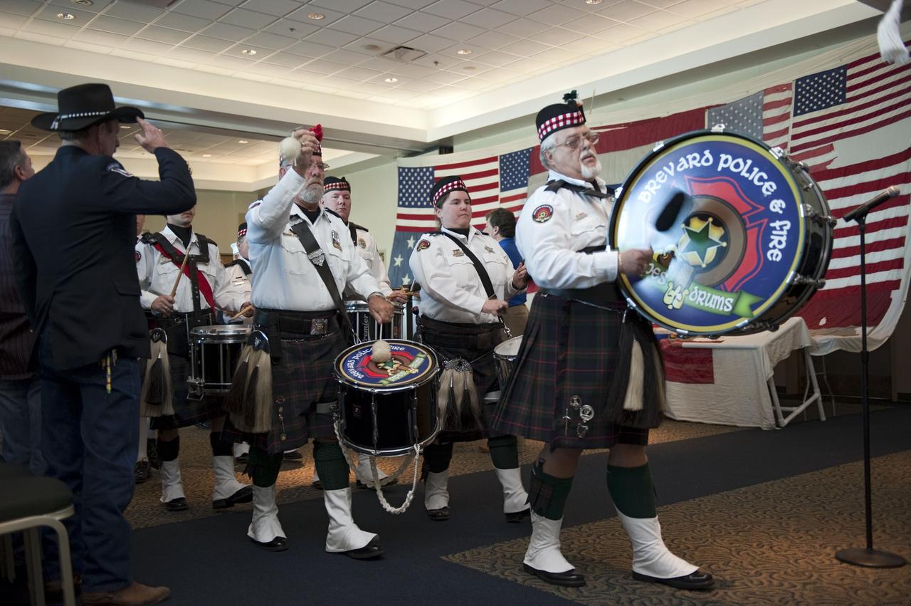 CAPE CANAVERAL, Fla. -- Members of the Brevard Police and Fire Pipes and Drums kick off the "The National 9/11 Flag" stitching ceremony in the Debus Conference Facility at the Kennedy Space Center Visitor Complex in Florida. The contributions of NASA, Kennedy Space Center and the state of Florida were stitched into the fabric of the American Flag, which was recovered near ground zero following the World Trade Center attacks on Sept. 11, 2001.       The "New York Says Thank You Foundation" is taking the flag on a cross-country journey to be restored to its original 13-stripe design using pieces of fabric from American flags destined for retirement in all 50 states. Once the flag is restored, it will become a permanent collection of the National September 11 Memorial Museum being built at the World Trade Center site. Photo credit: NASA/Kim Shiflett