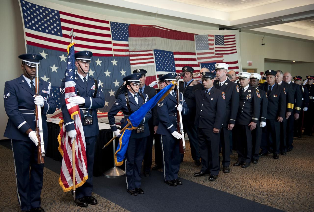 CAPE CANAVERAL, Fla. -- Members of the United States Air Force 45th Space Wing Honor Guard and more than a dozen 9/11 first responders take part in "The National 9/11 Flag" stitching ceremony in the Debus Conference Facility at the Kennedy Space Center Visitor Complex in Florida. The contributions of NASA, Kennedy Space Center and the state of Florida were stitched into the fabric of the American Flag, which was recovered near ground zero following the World Trade Center attacks on Sept. 11, 2001.         The "New York Says Thank You Foundation" is taking the flag on a cross-country journey to be restored to its original 13-stripe design using pieces of fabric from American flags destined for retirement in all 50 states. Once the flag is restored, it will become a permanent collection of the National September 11 Memorial Museum being built at the World Trade Center site. Photo credit: NASA/Kim Shiflett