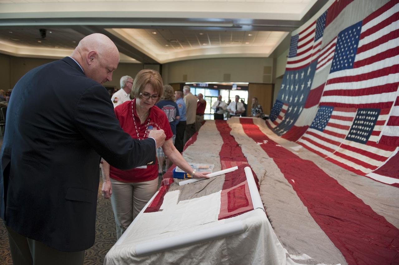 CAPE CANAVERAL, Fla. -- Joe Dowdy, special operations manager at NASA's Kennedy Space Center, contributes stitches to the "National 9/11 Flag" during a ceremony in the Debus Conference Facility at the Kennedy Space Center Visitor Complex in Florida. The contributions of NASA, Kennedy Space Center and the state of Florida were stitched into the fabric of the American Flag, which was recovered near ground zero following the World Trade Center attacks on Sept. 11, 2001.        The "New York Says Thank You Foundation" is taking the flag on a cross-country journey to be restored to its original 13-stripe design using pieces of fabric from American flags destined for retirement in all 50 states. Once the flag is restored, it will become a permanent collection of the National September 11 Memorial Museum being built at the World Trade Center site. Photo credit: NASA/Kim Shiflett