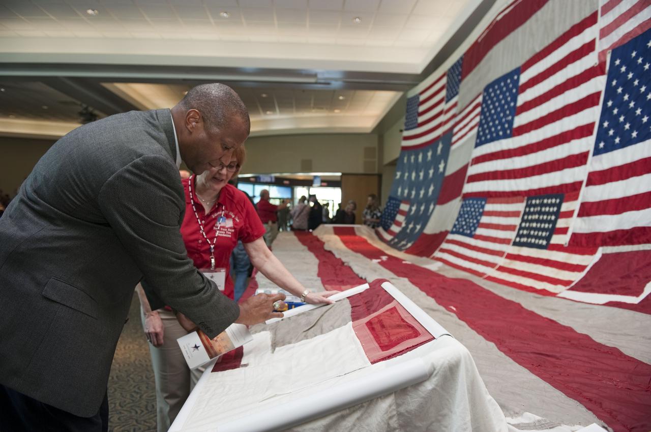 CAPE CANAVERAL, Fla. -- Kelvin Manning, associate director for Business Operations at NASA's Kennedy Space Center, contributes stitches to the "National 9/11 Flag" during a ceremony in the Debus Conference Facility at the Kennedy Space Center Visitor Complex in Florida. The contributions of NASA, Kennedy Space Center and the state of Florida were stitched into the fabric of the American Flag, which was recovered near ground zero following the World Trade Center attacks on Sept. 11, 2001.      The "New York Says Thank You Foundation" is taking the flag on a cross-country journey to be restored to its original 13-stripe design using pieces of fabric from American flags destined for retirement in all 50 states. Once the flag is restored, it will become a permanent collection of the National September 11 Memorial Museum being built at the World Trade Center site. Photo credit: NASA/Kim Shiflett