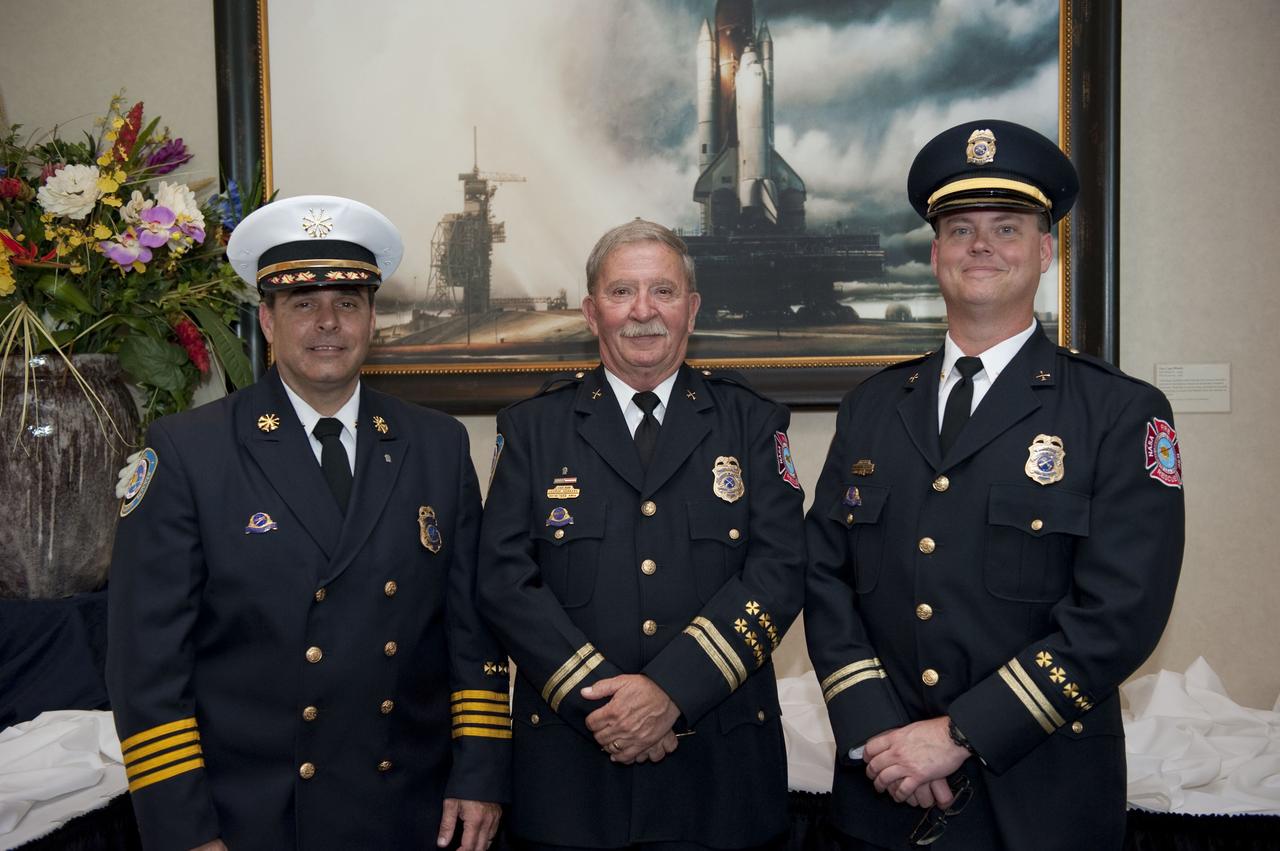 CAPE CANAVERAL, Fla. – Deputy Fire Chief Rick Anderson, left, Chief of Fire Training George Hoggard, and Assistant Chief of Fire Training David Seymour with NASA Kennedy Space Center Protective Services participated in the "National 9/11 Flag" stitching ceremony in the Debus Conference Facility at the Kennedy Space Center Visitor Complex in Florida. The contributions of NASA, Kennedy Space Center and the state of Florida were stitched into the fabric of the American Flag, which was recovered near ground zero following the World Trade Center attacks on Sept. 11, 2001.      The "New York Says Thank You Foundation" is taking the flag on a cross-country journey to be restored to its original 13-stripe design using pieces of fabric from American flags destined for retirement in all 50 states. Once the flag is restored, it will become a permanent collection of the National September 11 Memorial Museum being built at the World Trade Center site. Photo credit: NASA/Kim Shiflett