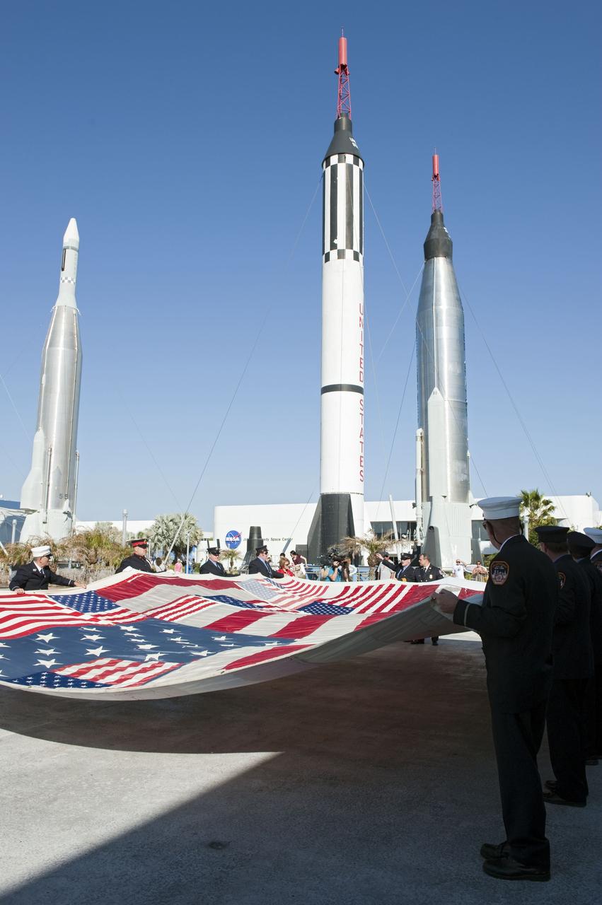 CAPE CANAVERAL, Fla. -- "The National 9/11 Flag" is transported from the Debus Conference Facility to the Rocket Garden at the Kennedy Space Center Visitor Complex in Florida. The contributions of NASA, Kennedy Space Center and the state of Florida were stitched into the fabric of the American Flag, which was recovered near ground zero following the World Trade Center attacks on Sept. 11, 2001.     The "New York Says Thank You Foundation" is taking the flag on a cross-country journey to be restored to its original 13-stripe design using pieces of fabric from American flags destined for retirement in all 50 states. Once the flag is restored, it will become a permanent collection of the National September 11 Memorial Museum being built at the World Trade Center site. Photo credit: NASA/Kim Shiflett