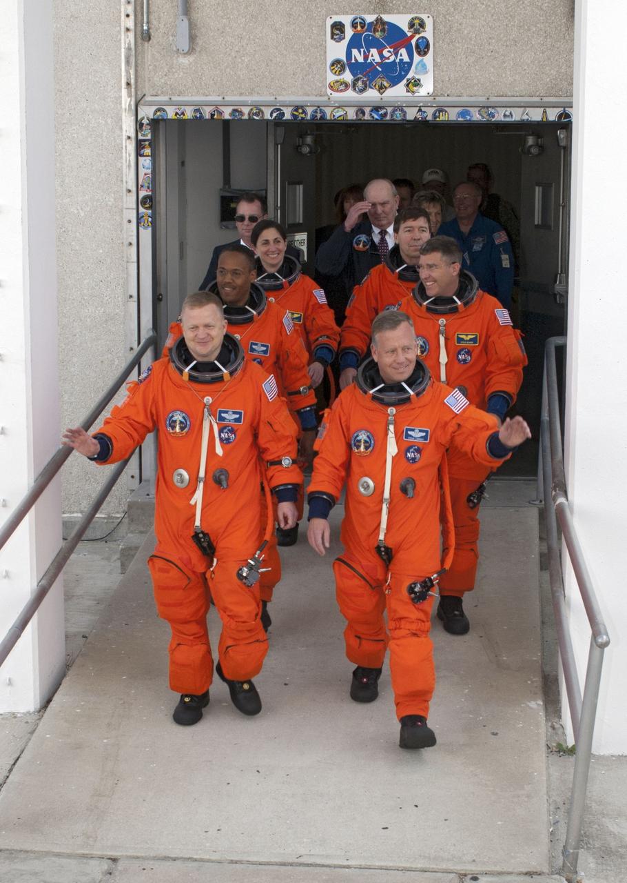 CAPE CANAVERAL, Fla. -- At NASA's Kennedy Space Center in Florida, space shuttle Discovery's STS-133 astronauts, dressed in their orange launch-and-entry suits, wave to news media representatives and other spectators as they walk out of the Operations and Checkout Building towards the Astrovan, which will transport them to Launch Pad 39A. From back row left, are Mission Specialists Nicole Stott, Michael Barratt, middle row left, Mission Specialists Alvin Drew and Steve Bowen; front row left, Pilot Eric Boe; and Commander Steve Lindsey. Discovery and its six-member crew will deliver the Permanent Multipurpose Module, packed with supplies and critical spare parts, as well as Robonaut 2, the dexterous humanoid astronaut helper, to the International Space Station. Discovery, which will fly its 39th mission, is scheduled to be retired following STS-133. This will be the 133rd Space Shuttle Program mission and the 35th shuttle voyage to the space station. For more information on the STS-133 mission, visit www.nasa.gov/mission_pages/shuttle/shuttlemissions/sts133/. Photo credit: NASA/Kim Shiflett