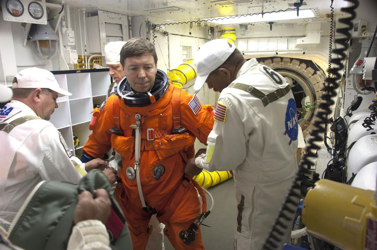CAPE CANAVERAL, Fla. - In the White Room at Launch Pad 39A at NASA's Kennedy Space Center in Florida, United Space Alliance spacesuit technicians help STS-133 Mission Specialist Michael Barratt put on the parachute for his launch-and-entry suit before he enters space shuttle Discovery through the crew hatch in the background. Michael Barratt is making his first flight aboard a space shuttle. Barratt has called the space station home before, though, after spending 199 days as a crew member of Expeditions 19 and 20 in 2009. Scheduled to lift off Feb. 24 at 4:50 p.m. EST, Discovery and its crew will deliver the Permanent Multipurpose Module, packed with supplies and critical spare parts, as well as Robonaut 2, the dexterous humanoid astronaut helper, to the International Space Station. Discovery, which will fly its 39th mission, is scheduled to be retired following STS-133. This will be the 133rd Space Shuttle Program mission and the 35th shuttle voyage to the space station. For more information on the STS-133 mission, visit www.nasa.gov/mission_pages/shuttle/shuttlemissions/sts133/. Photo credit: NASA/Sandra Joseph and Kevin O'Connell