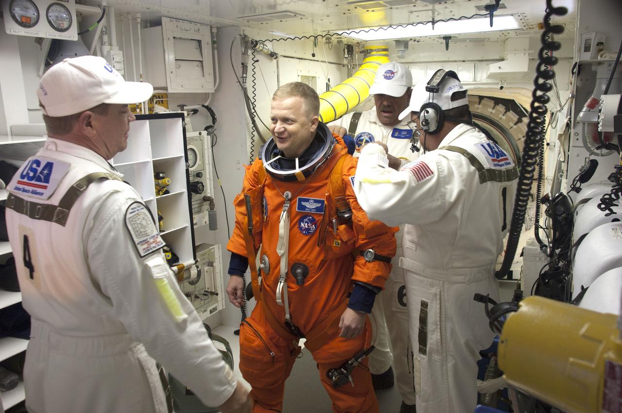 CAPE CANAVERAL, Fla. - In the White Room at Launch Pad 39A at NASA's Kennedy Space Center in Florida, United Space Alliance spacesuit technicians help STS-133 Pilot Eric Boe put on the parachute for his launch-and-entry suit before he enters space shuttle Discovery through the crew hatch in the background. Boe last piloted space shuttle Endeavour during its STS-126 mission back in 2008. Scheduled to lift off Feb. 24 at 4:50 p.m. EST, Discovery and its crew will deliver the Permanent Multipurpose Module, packed with supplies and critical spare parts, as well as Robonaut 2, the dexterous humanoid astronaut helper, to the International Space Station. Discovery, which will fly its 39th mission, is scheduled to be retired following STS-133. This will be the 133rd Space Shuttle Program mission and the 35th shuttle voyage to the space station. For more information on the STS-133 mission, visit www.nasa.gov/mission_pages/shuttle/shuttlemissions/sts133/. Photo credit: NASA/Sandra Joseph and Kevin O'Connell
