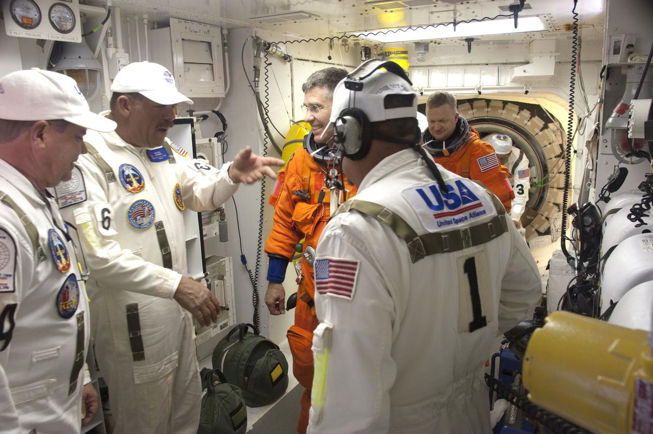 CAPE CANAVERAL, Fla. - In the White Room at Launch Pad 39A at NASA's Kennedy Space Center in Florida, United Space Alliance spacesuit technicians help STS-133 Mission Specialist Steve Bowen put on the parachute for his launch-and-entry suit before he enters space shuttle Discovery through the crew hatch in the background. Bowen, who is making his third spaceflight last flew in May 2010 on the STS-132 mission. Bowen replaces astronaut Tim Kopra as Mission Specialist 2, because Kopra was injured in a recent bicycle accident that prevented him from lifting off during this launch window. Behind Bowen is STS-133 Pilot Eric Boe. Scheduled to lift off Feb. 24 at 4:50 p.m. EST, Discovery and its crew will deliver the Permanent Multipurpose Module, packed with supplies and critical spare parts, as well as Robonaut 2, the dexterous humanoid astronaut helper, to the International Space Station. Discovery, which will fly its 39th mission, is scheduled to be retired following STS-133. This will be the 133rd Space Shuttle Program mission and the 35th shuttle voyage to the space station. For more information on the STS-133 mission, visit www.nasa.gov/mission_pages/shuttle/shuttlemissions/sts133/. Photo credit: NASA/Sandra Joseph and Kevin O'Connell