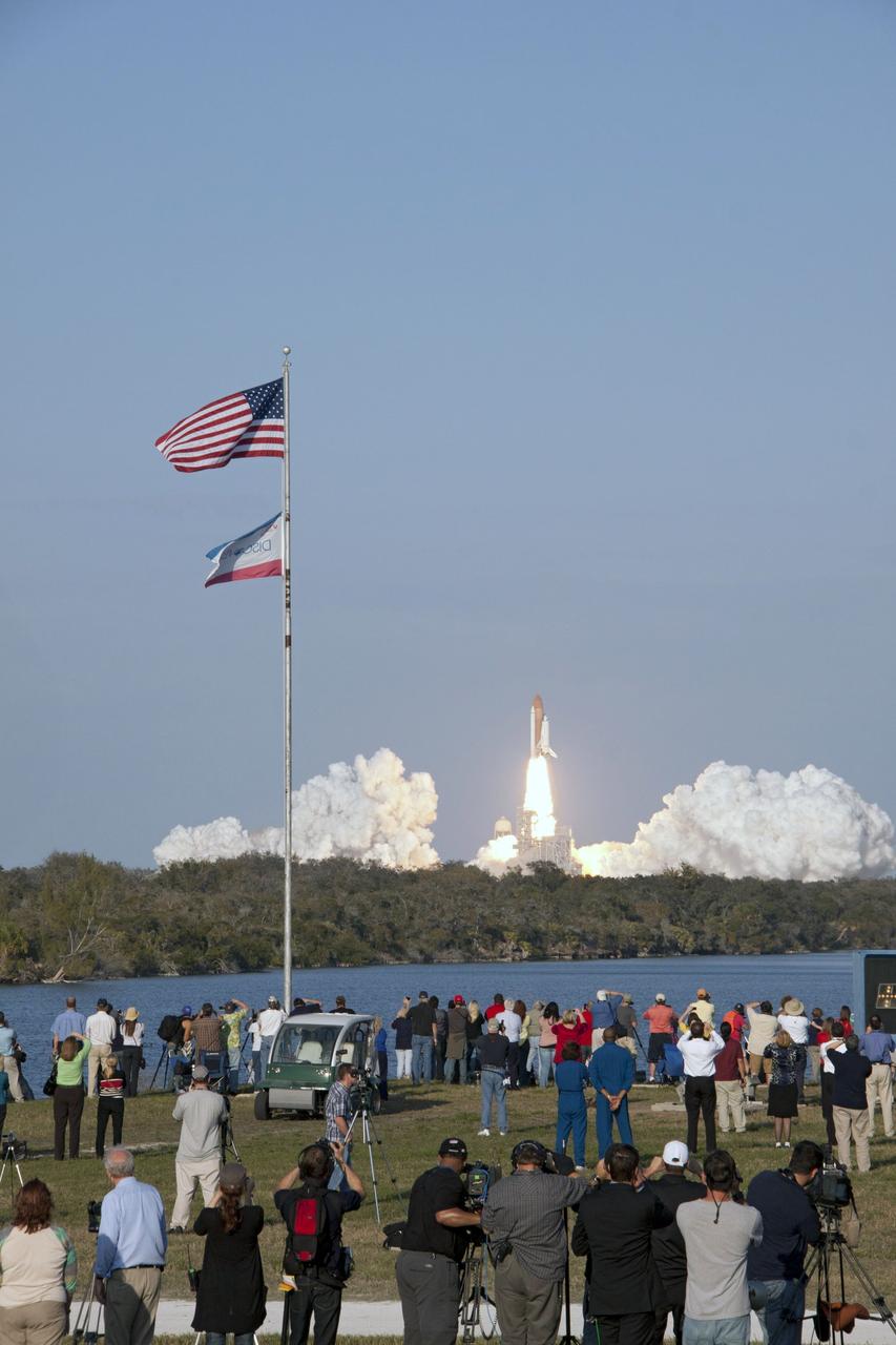 CAPE CANAVERAL, Fla. - Space shuttle Discovery's liftoff from Launch Pad 39A at NASA's Kennedy Space Center in Florida on a picturesque, warm, late February afternoon is witnessed by news media representatives near the countdown clock at the Press Site. Launch of the STS-133 mission was at 4:53 p.m. EST on Feb. 24.           Discovery and its six-member crew are on a mission to deliver the Permanent Multipurpose Module, packed with supplies and critical spare parts, as well as Robonaut 2, the dexterous humanoid astronaut helper, to the International Space Station. Discovery is making its 39th mission and is scheduled to be retired following STS-133. This is the 133rd Space Shuttle Program mission and the 35th shuttle voyage to the space station. For more information on the STS-133 mission, visit www.nasa.gov/mission_pages/shuttle/shuttlemissions/sts133/.  Photo credit: NASA/Troy Cryder