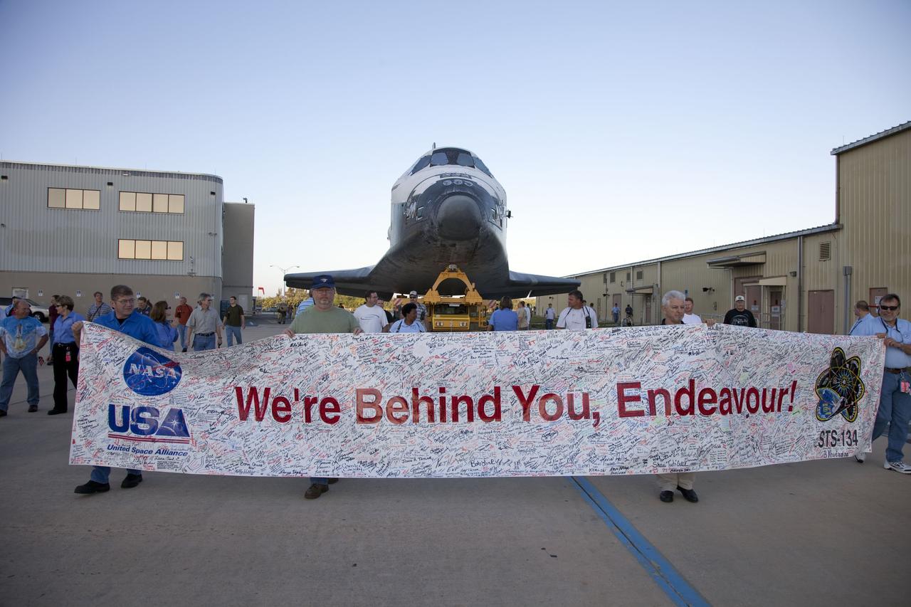 CAPE CANAVERAL, Fla. -- At NASA's Kennedy Space Center in Florida, employees hold up a banner to commemorate space shuttle Endeavour's STS-134 mission as it is transported from Orbiter Processing Facility-2 to the Vehicle Assembly Building.          Endeavour and its STS-134 crew will deliver the Express Logistics Carrier-3, Alpha Magnetic Spectrometer, spare parts, a high-pressure gas tank, additional spare parts for Dextre and micrometeoroid debris shields to the International Space Station. Launch is targeted for April 19 at 7:48 p.m. EDT. For more information visit, http://www.nasa.gov/mission_pages/shuttle/shuttlemissions/sts134/index.html. Photo credit: NASA/Frankie Martin