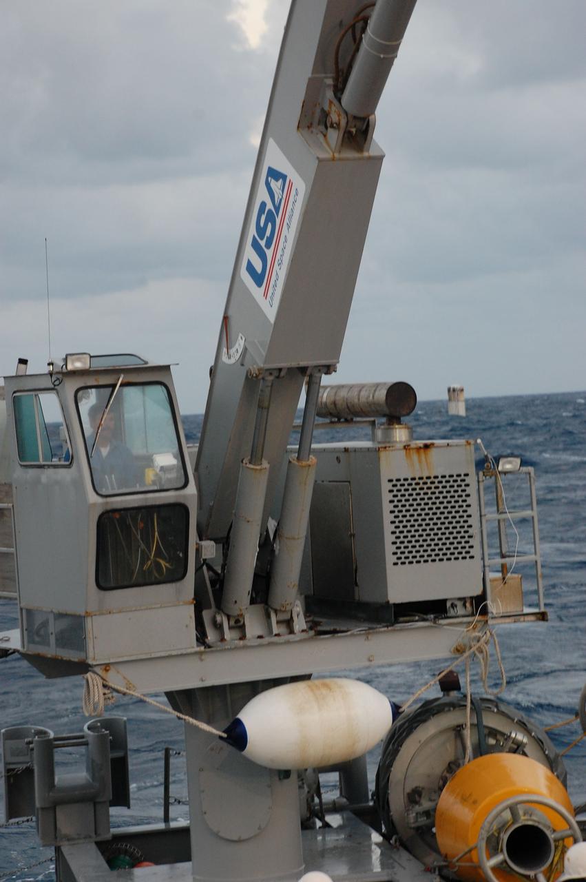 CAPE CANAVERAL, Fla. -- A worker on Freedom Star, one of NASA's solid rocket booster retrieval ships, manipulates a crane to recover the left solid rocket booster from the Atlantic Ocean after space shuttle Discovery's STS-133 launch.        The shuttle’s two solid rocket booster casings and associated flight hardware are recovered in the Atlantic Ocean after every launch by Liberty Star and Freedom Star. The boosters impact the Atlantic about seven minutes after liftoff and the retrieval ships are stationed about 10 miles from the impact area at the time of splashdown. After the spent segments are processed, they will be transported to Utah, where they will be refurbished and stored, if needed. Photo credit: NASA/Ben Smegelsky