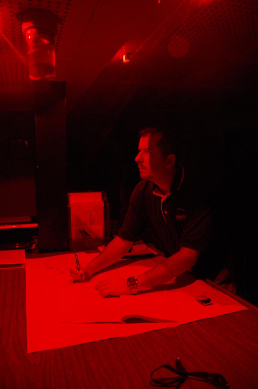 CAPE CANAVERAL, Fla. -- Chief Mate Jamie Harris works at the chart table on the bridge at night under a red light so as not to compromise night vision on Freedom Star, one of NASA's solid rocket booster retrieval ships plotting a course in the direction of the left spent booster that splashed down into the Atlantic Ocean after space shuttle Discovery's STS-133 launch.          The shuttle’s two solid rocket booster casings and associated flight hardware are recovered in the Atlantic Ocean after every launch by Liberty Star and Freedom Star. The boosters impact the Atlantic about seven minutes after liftoff and the retrieval ships are stationed about 10 miles from the impact area at the time of splashdown. After the spent segments are processed, they will be transported to Utah, where they will be refurbished and stored, if needed. Photo credit: NASA/Ben Smegelsky