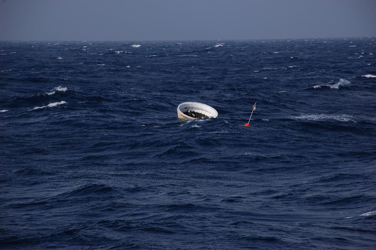 CAPE CANAVERAL, Fla. -- After splashing down, the nose cap of the left spent booster bobs in the Atlantic Ocean as Freedom Star, one of NASA's solid rocket booster retrieval ships makes its way closer for recovery following space shuttle Discovery's STS-133 launch.      The shuttle’s two solid rocket booster casings and associated flight hardware are recovered in the Atlantic Ocean after every launch by Liberty Star and Freedom Star. The boosters impact the Atlantic about seven minutes after liftoff and the retrieval ships are stationed about 10 miles from the impact area at the time of splashdown. After the spent segments are processed, they will be transported to Utah, where they will be refurbished and stored, if needed. Photo credit: NASA/Ben Smegelsky