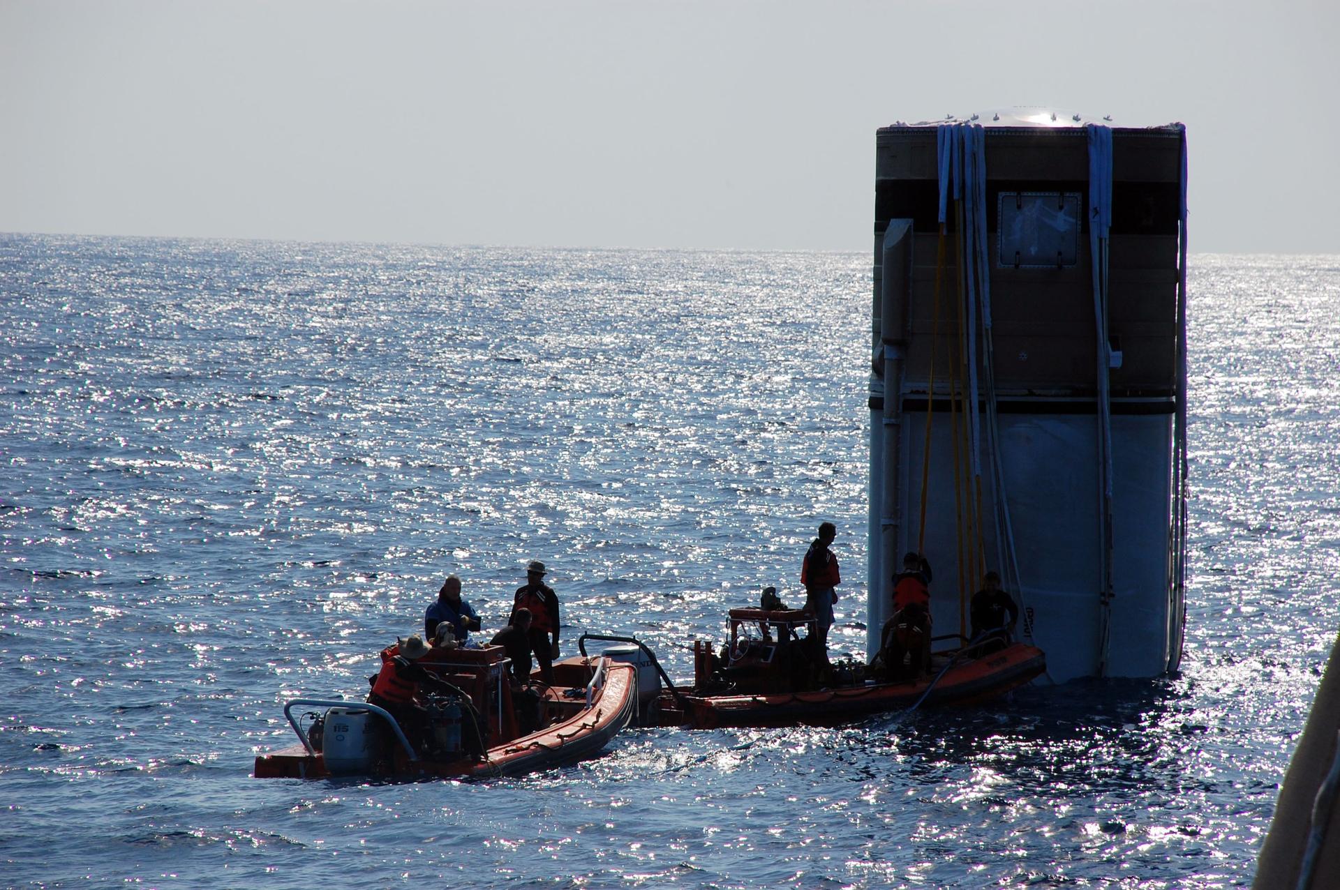 Crew members from Freedom Star, one of NASA's solid rocket booster retrieval ships, approach the left spent booster bobbing in the Atlantic Ocean
