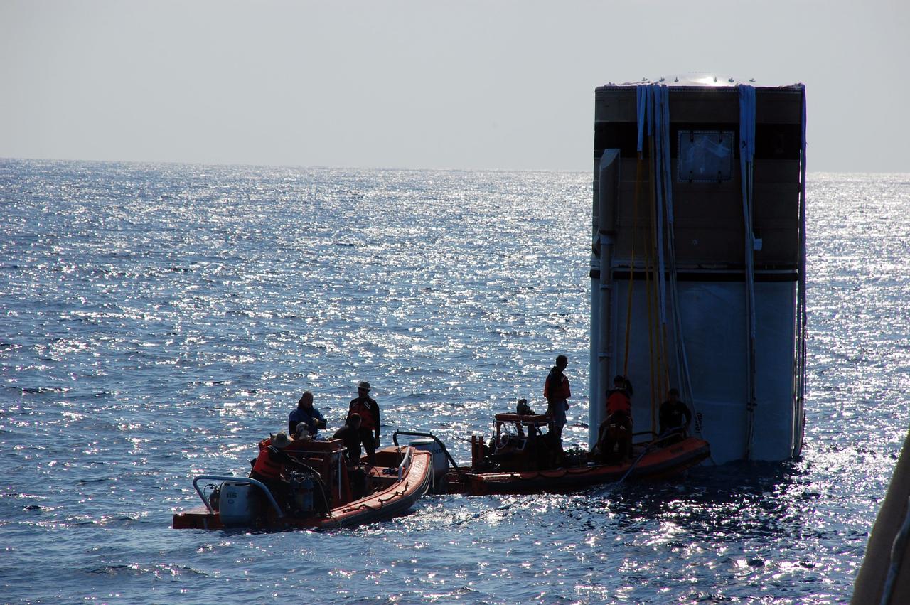 CAPE CANAVERAL, Fla. -- Crew members from Freedom Star, one of NASA's solid rocket booster retrieval ships, approach the left spent booster bobbing in the Atlantic Ocean to attach a hose that will facilitate debris and water clearing and the pumping in of air so the booster can float horizontally on the water's surface for towing back to Port Canaveral in Florida.        The shuttle’s two solid rocket booster casings and associated flight hardware are recovered in the Atlantic Ocean after every launch by Liberty Star and Freedom Star. The boosters impact the Atlantic about seven minutes after liftoff and the retrieval ships are stationed about 10 miles from the impact area at the time of splashdown. After the spent segments are processed, they will be transported to Utah, where they will be refurbished and stored, if needed. Photo credit: NASA/Ben Smegelsky