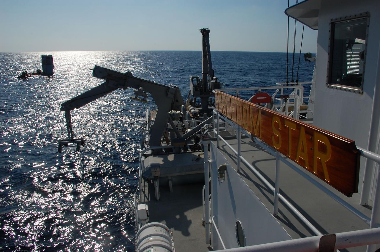 CAPE CANAVERAL, Fla. -- A crane is prepared to pluck the returning skiffs out of the water after crew members from Freedom Star, one of NASA's solid rocket booster retrieval ships, attached a hose between the left spent booster and the vessel that will facilitate debris and water clearing and the pumping in of air into the booster so it can float horizontally on the water's surface for towing back to Port Canaveral in Florida.              The shuttle’s two solid rocket booster casings and associated flight hardware are recovered in the Atlantic Ocean after every launch by Liberty Star and Freedom Star. The boosters impact the Atlantic about seven minutes after liftoff and the retrieval ships are stationed about 10 miles from the impact area at the time of splashdown. After the spent segments are processed, they will be transported to Utah, where they will be refurbished and stored, if needed. Photo credit: NASA/Ben Smegelsky