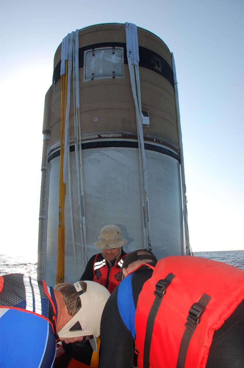 CAPE CANAVERAL, Fla. -- Crew members in a skiff from Freedom Star, one of NASA's solid rocket booster retrieval ships, attach a hose between the left spent booster and the vessel that will facilitate debris and water clearing and the pumping in of air in so the booster can float horizontally on the water's surface for towing back to Port Canaveral in Florida.            The shuttle’s two solid rocket booster casings and associated flight hardware are recovered in the Atlantic Ocean after every launch by Liberty Star and Freedom Star. The boosters impact the Atlantic about seven minutes after liftoff and the retrieval ships are stationed about 10 miles from the impact area at the time of splashdown. After the spent segments are processed, they will be transported to Utah, where they will be refurbished and stored, if needed. Photo credit: NASA/Ben Smegelsky