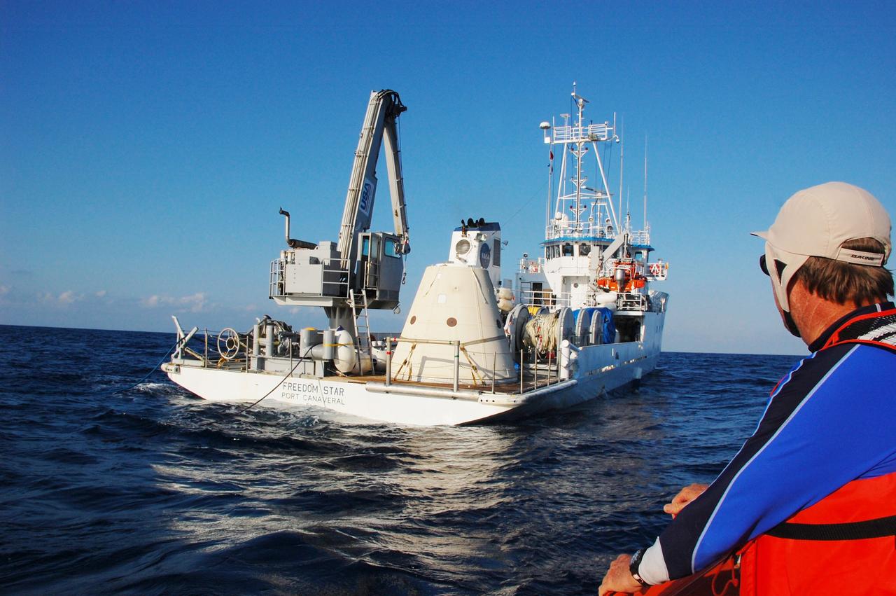 CAPE CANAVERAL, Fla. -- Crew members in a skiff from Freedom Star, one of NASA's solid rocket booster retrieval ships, look back at the vessel toward the left spent booster nose cap, which was recovered from the Atlantic Ocean and now secured on the deck for delivery back to Port Canaveral in Florida.      The shuttle’s two solid rocket booster casings and associated flight hardware are recovered in the Atlantic Ocean after every launch by Liberty Star and Freedom Star. The boosters impact the Atlantic about seven minutes after liftoff and the retrieval ships are stationed about 10 miles from the impact area at the time of splashdown. After the spent segments are processed, they will be transported to Utah, where they will be refurbished and stored, if needed. Photo credit: NASA/Ben Smegelsky