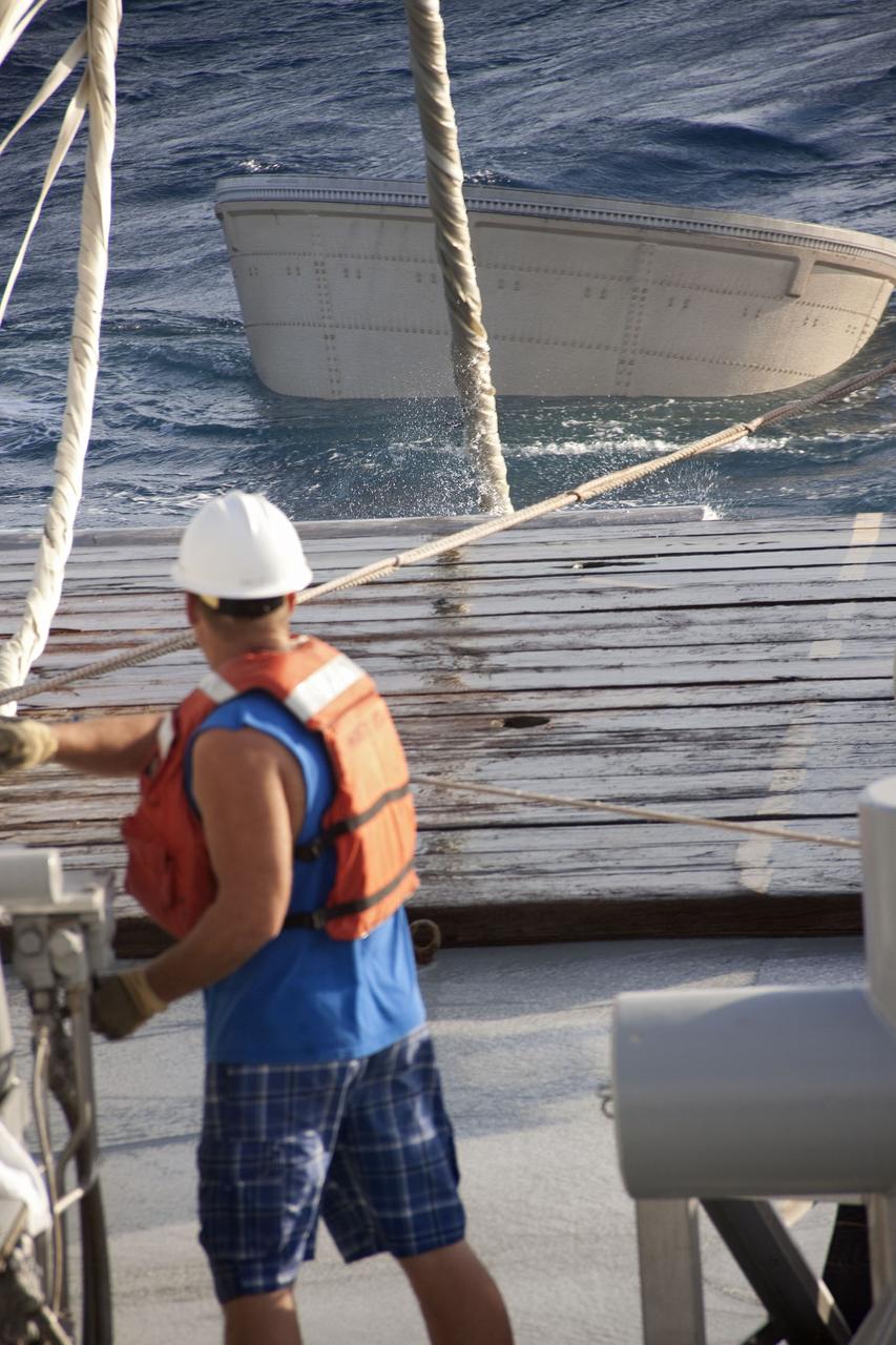 CAPE CANAVERAL, Fla. -- A crew member on Liberty Star, one of NASA's solid rocket booster retrieval ships, uses a crane to haul the right booster nose cap out of the Atlantic Ocean that splashed down after Discovery's final launch.          The shuttle’s two solid rocket booster casings and associated flight hardware are recovered in the Atlantic Ocean after every launch by Freedom Star and Liberty Star. The boosters impact the Atlantic about seven minutes after liftoff and the retrieval ships are stationed about 10 miles from the impact area at the time of splashdown. After the spent segments are processed, they will be transported to Utah, where they will be refurbished and stored, if needed. Photo credit: NASA/Frank Michaux