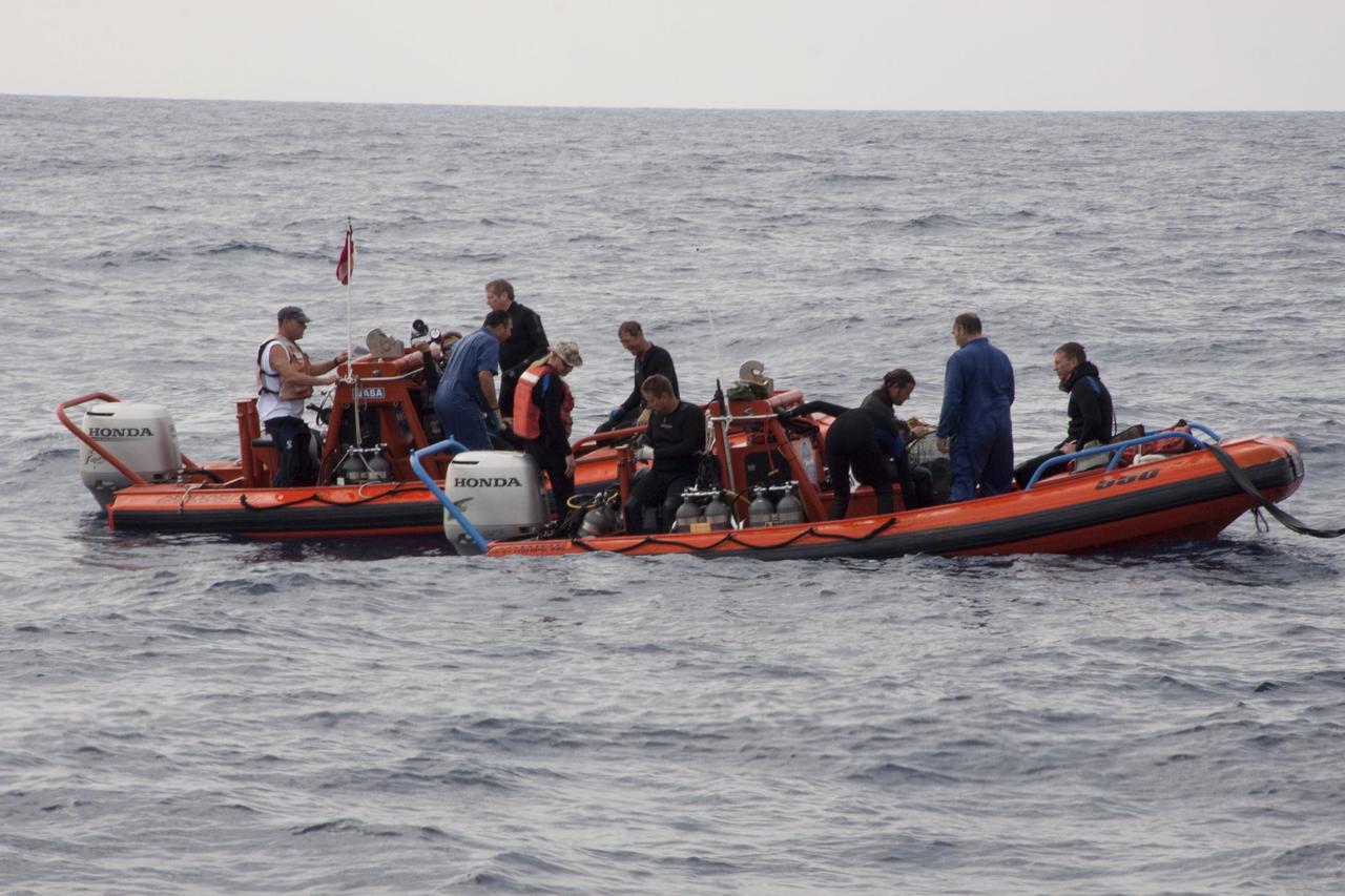 CAPE CANAVERAL, Fla. -- Crew members and divers in skiffs from Liberty Star, one of NASA's solid rocket booster retrieval ships, are prepared to retrieve the parachute lines from the right spent booster bobbing in the Atlantic Ocean from space shuttle Discovery's final launch.                    The shuttle's two solid rocket booster casings and associated flight hardware are recovered in the Atlantic Ocean after every launch by Freedom Star and Liberty Star. The boosters impact the Atlantic about seven minutes after liftoff and the retrieval ships are stationed about 10 miles from the impact area at the time of splashdown. After the spent segments are processed, they will be transported to Utah, where they will be refurbished and stored, if needed. Photo credit: NASA/Frank Michaux