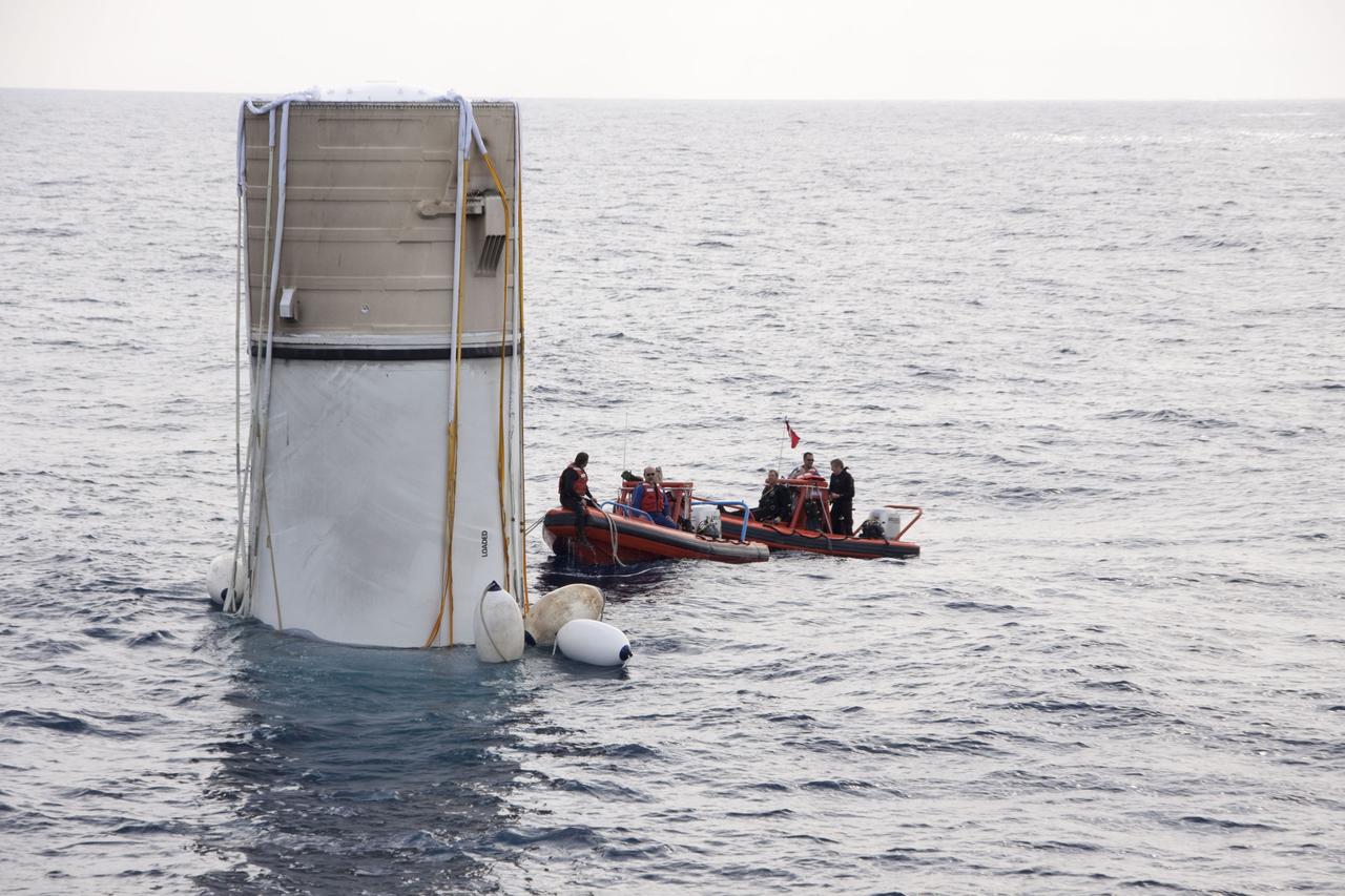 CAPE CANAVERAL, Fla. -- Crew members in a skiff from Liberty Star, one of NASA's solid rocket booster retrieval ships, attach flotation devices, or buoys, to the parachute lines from the right spent booster from space shuttle Discovery's final launch.                       The shuttle's two solid rocket booster casings and associated flight hardware are recovered in the Atlantic Ocean after every launch by Freedom Star and Liberty Star. The boosters impact the Atlantic about seven minutes after liftoff and the retrieval ships are stationed about 10 miles from the impact area at the time of splashdown. After the spent segments are processed, they will be transported to Utah, where they will be refurbished and stored, if needed. Photo credit: NASA/Frank Michaux