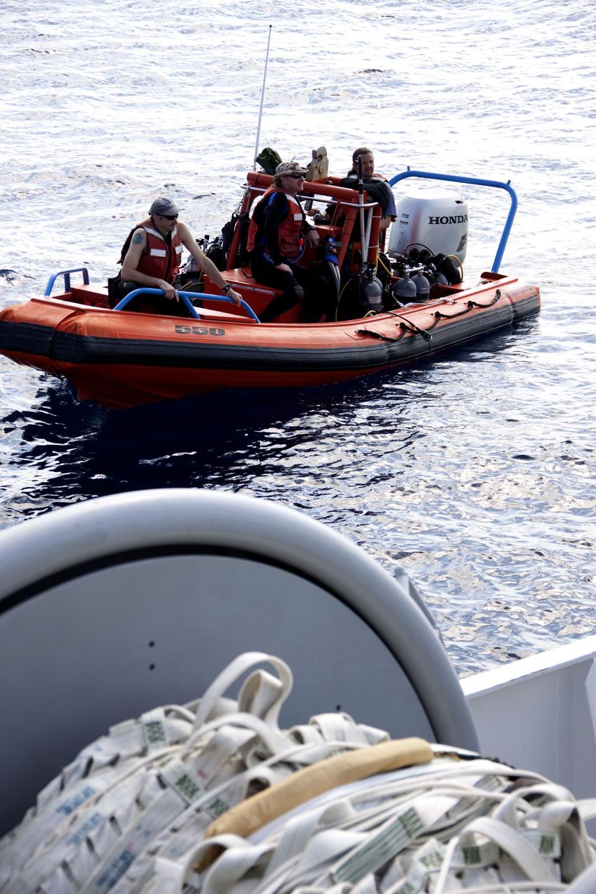 CAPE CANAVERAL, Fla. -- Crew members return to Liberty Star, one of NASA's solid rocket booster retrieval ships, in a skiff after the massive parachute from the right spent booster has been hauled on board from space shuttle Discovery's final launch.                  The shuttle's two solid rocket booster casings and associated flight hardware are recovered in the Atlantic Ocean after every launch by Freedom Star and Liberty Star. The boosters impact the Atlantic about seven minutes after liftoff and the retrieval ships are stationed about 10 miles from the impact area at the time of splashdown. After the spent segments are processed, they will be transported to Utah, where they will be refurbished and stored, if needed. Photo credit: NASA/Frank Michaux