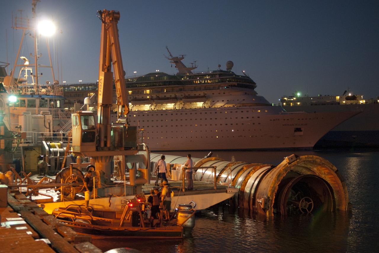 CAPE CANAVERAL, Fla. -- The Solid Rocket Booster Retrieval Ship Freedom Star, with a booster in tow, is docked in Port Canaveral in Florida before continuing on to Hangar AF at Cape Canaveral Air Force Station. A cruise ship is seen in the background. The booster was used during space shuttle Discovery's STS-133 launch from NASA Kennedy Space Center's Launch Pad 39A on Feb. 24. The shuttle’s two solid rocket booster casings and associated flight hardware are recovered in the Atlantic Ocean after every launch by Liberty Star and Freedom Star.                    The boosters impact the Atlantic about seven minutes after liftoff and the retrieval ships are stationed about 10 miles from the impact area at the time of splashdown.  After the spent segments are processed, they will be transported to Utah, where they will be refurbished and stored, if needed. Photo credit: NASA/Jim Grossmann