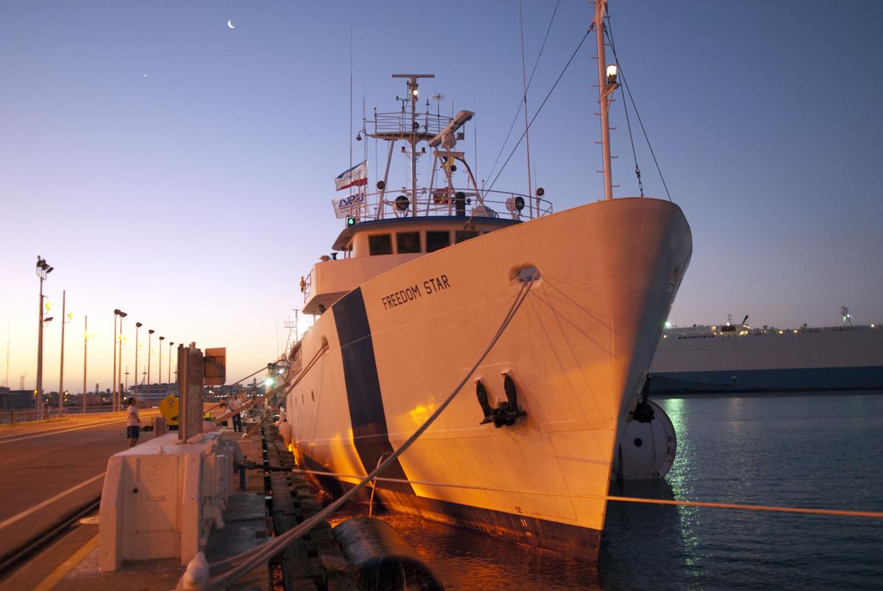 CAPE CANAVERAL, Fla. -- The Solid Rocket Booster Retrieval Ship Freedom Star, with a booster in tow, is docked in Port Canaveral in Florida before continuing on to Hangar AF at Cape Canaveral Air Force Station. A cruise ship is seen in the background. The booster was used during space shuttle Discovery's STS-133 launch from NASA Kennedy Space Center's Launch Pad 39A on Feb. 24. The shuttle’s two solid rocket booster casings and associated flight hardware are recovered in the Atlantic Ocean after every launch by Liberty Star and Freedom Star.                  The boosters impact the Atlantic about seven minutes after liftoff and the retrieval ships are stationed about 10 miles from the impact area at the time of splashdown.  After the spent segments are processed, they will be transported to Utah, where they will be refurbished and stored, if needed. Photo credit: NASA/Jim Grossmann