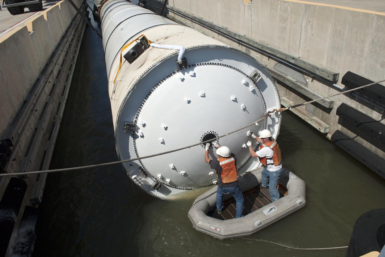 CAPE CANAVERAL, Fla. -- Workers in a small raft, guide the left spent booster used during space shuttle Discovery's final launch into position in a hoisting slip at the Solid Rocket Booster Disassembly Facility at Hangar AF on Cape Canaveral Air Force Station in Florida. The shuttle's two solid rocket booster casings and associated flight hardware are recovered in the Atlantic Ocean after every launch by Freedom Star and Liberty Star. The boosters impact the Atlantic about seven minutes after liftoff and the retrieval ships are stationed about 10 miles from the impact area at the time of splashdown. After the spent segments are processed, they will be transported to Utah, where they will be refurbished and stored, if needed. Photo credit: NASA/Jim Grossmann
