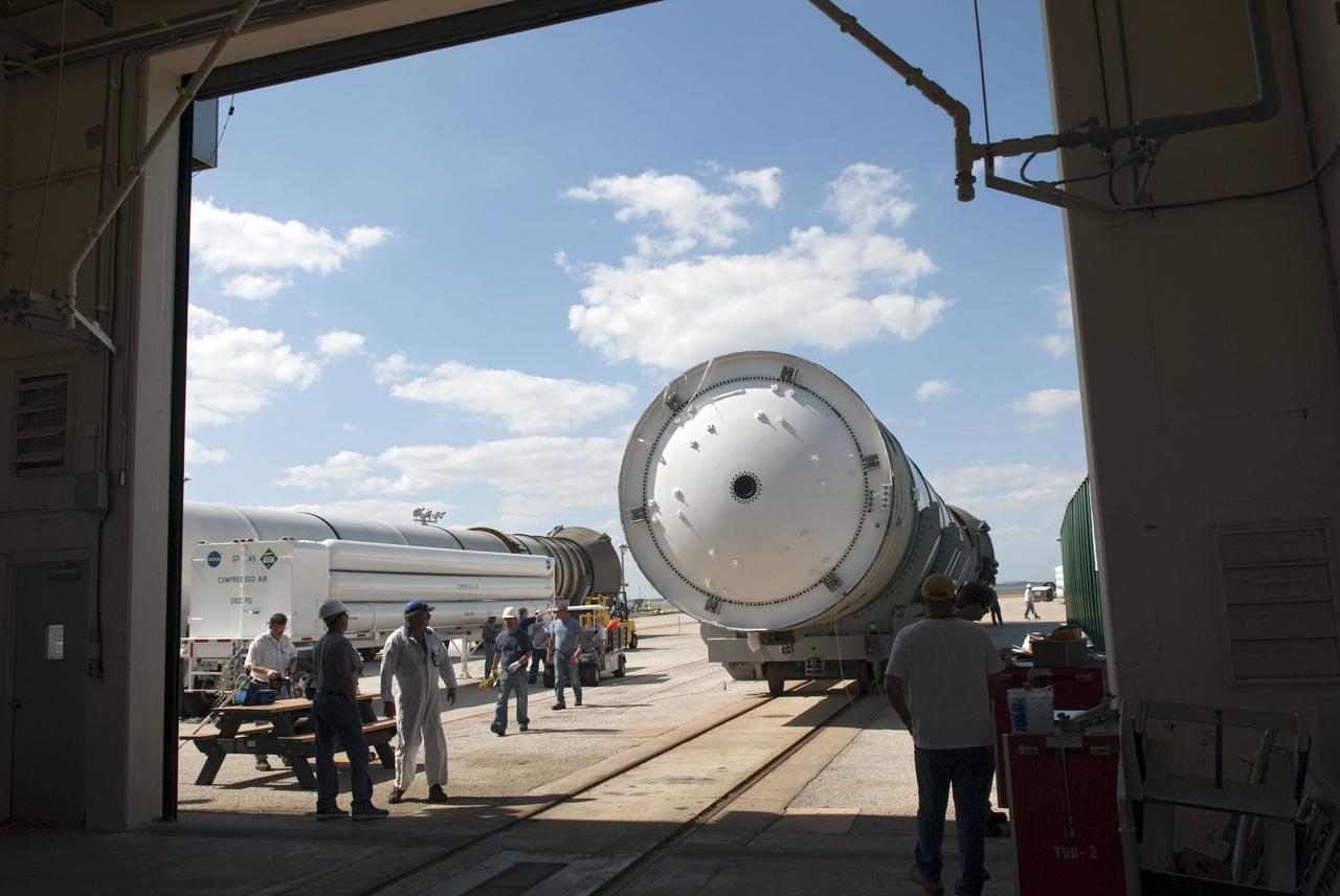 CAPE CANAVERAL, Fla. -- Workers at the Solid Rocket Booster Disassembly Facility at Hangar AF on Cape Canaveral Air Force Station in Florida, accompany the left spent booster, used during space shuttle Discovery's final launch, into the building for processing. The shuttle's two solid rocket booster casings and associated flight hardware are recovered in the Atlantic Ocean after every launch by Freedom Star and Liberty Star. The boosters impact the Atlantic about seven minutes after liftoff and the retrieval ships are stationed about 10 miles from the impact area at the time of splashdown. After the spent segments are processed, they will be transported to Utah, where they will be refurbished and stored, if needed. Photo credit: NASA/Jim Grossmann